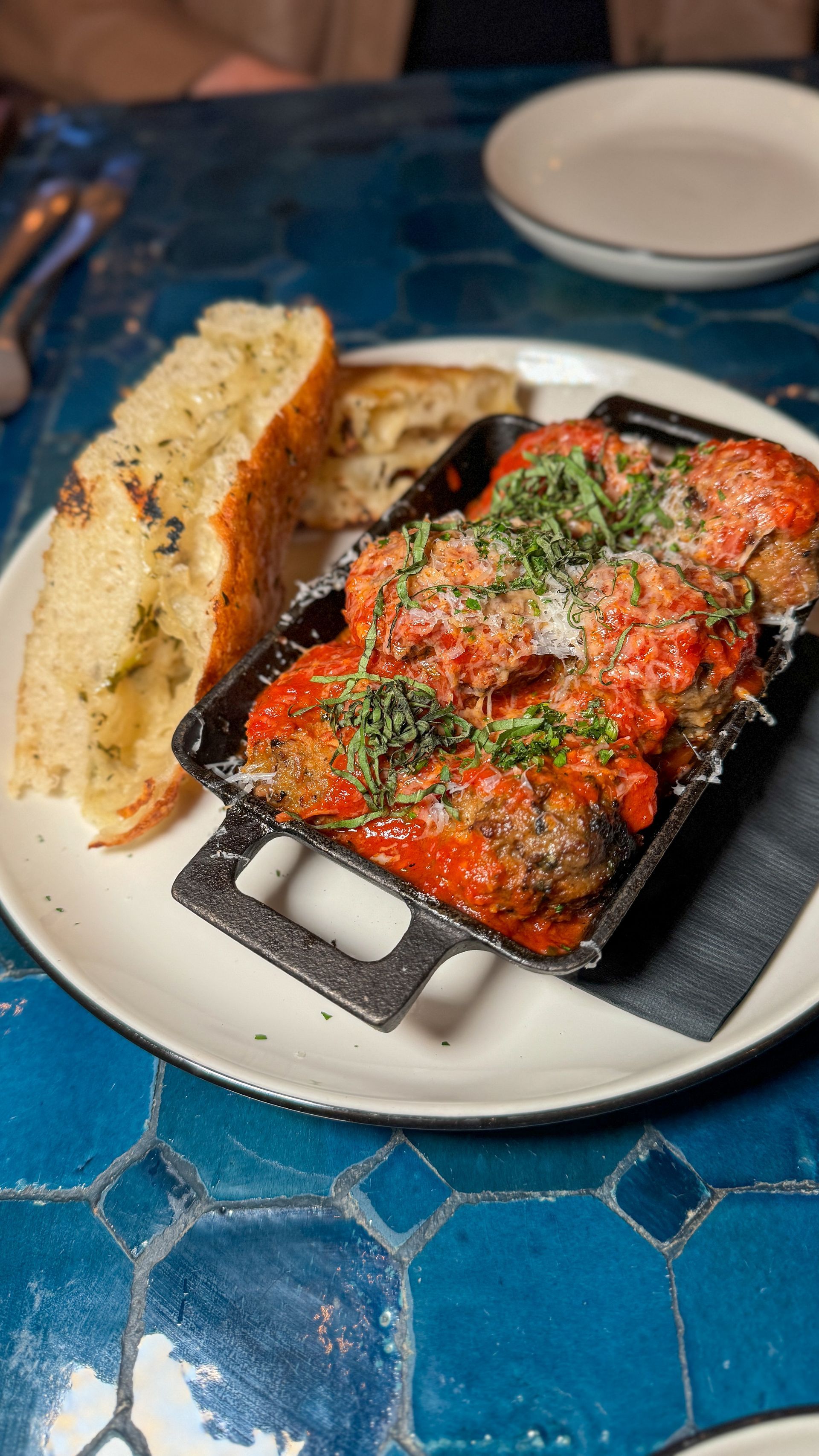 A plate of meatballs and garlic bread on a table.