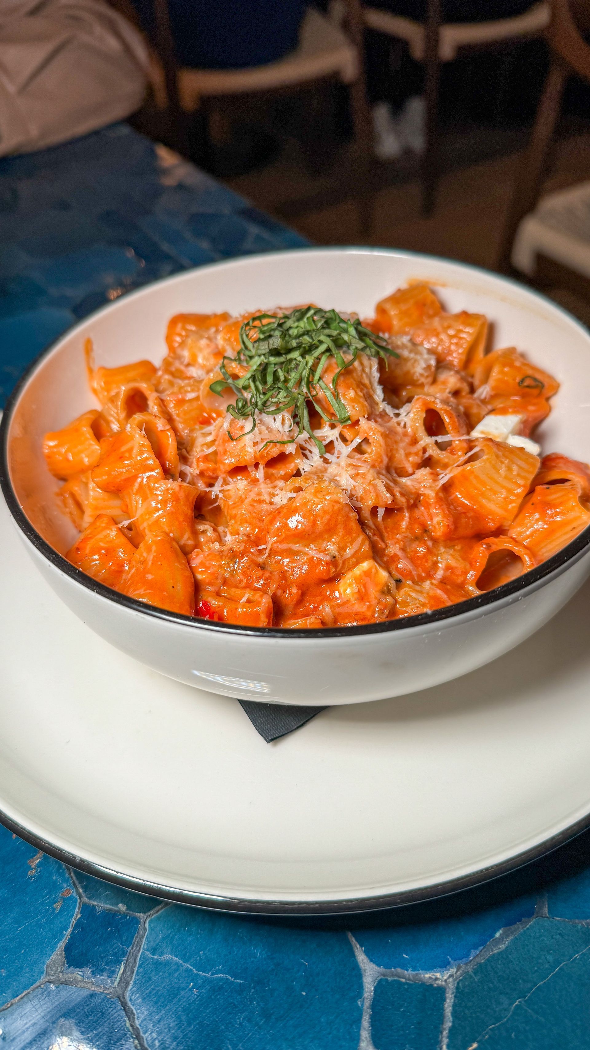 A close up of a bowl of pasta on a plate on a table.