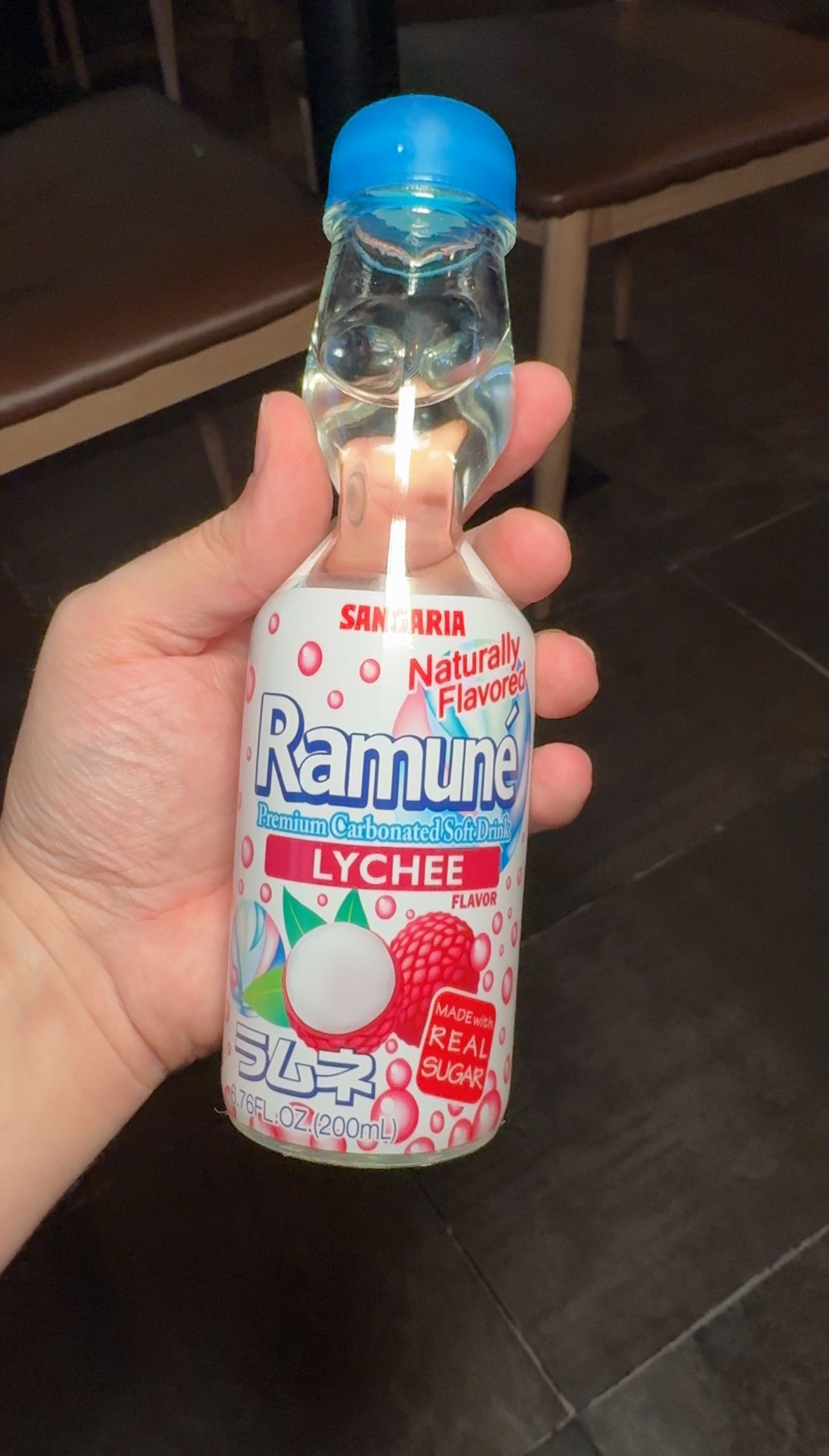 A person is holding a bottle of lychee flavored soda.