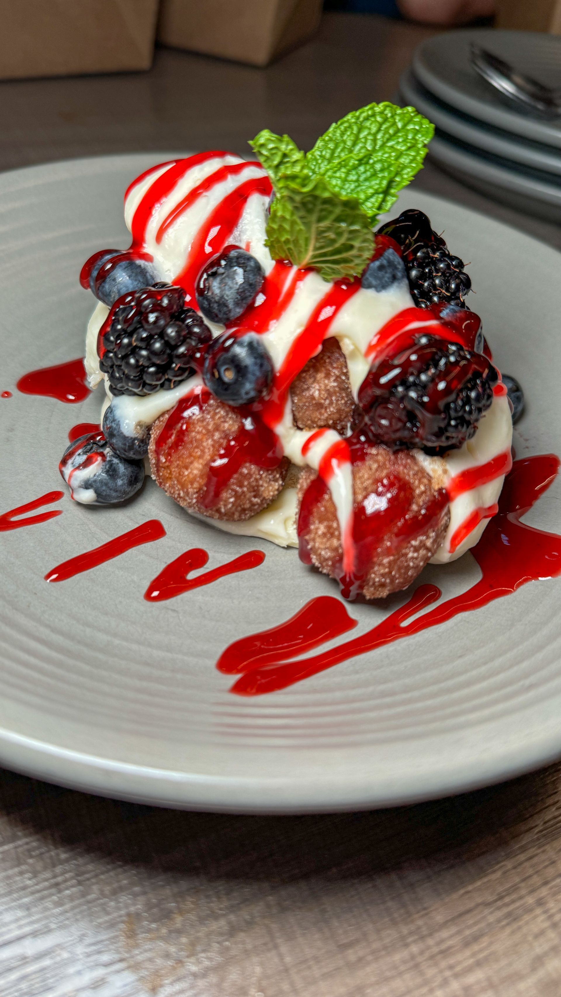 A dessert with ice cream and berries on a plate on a table.
