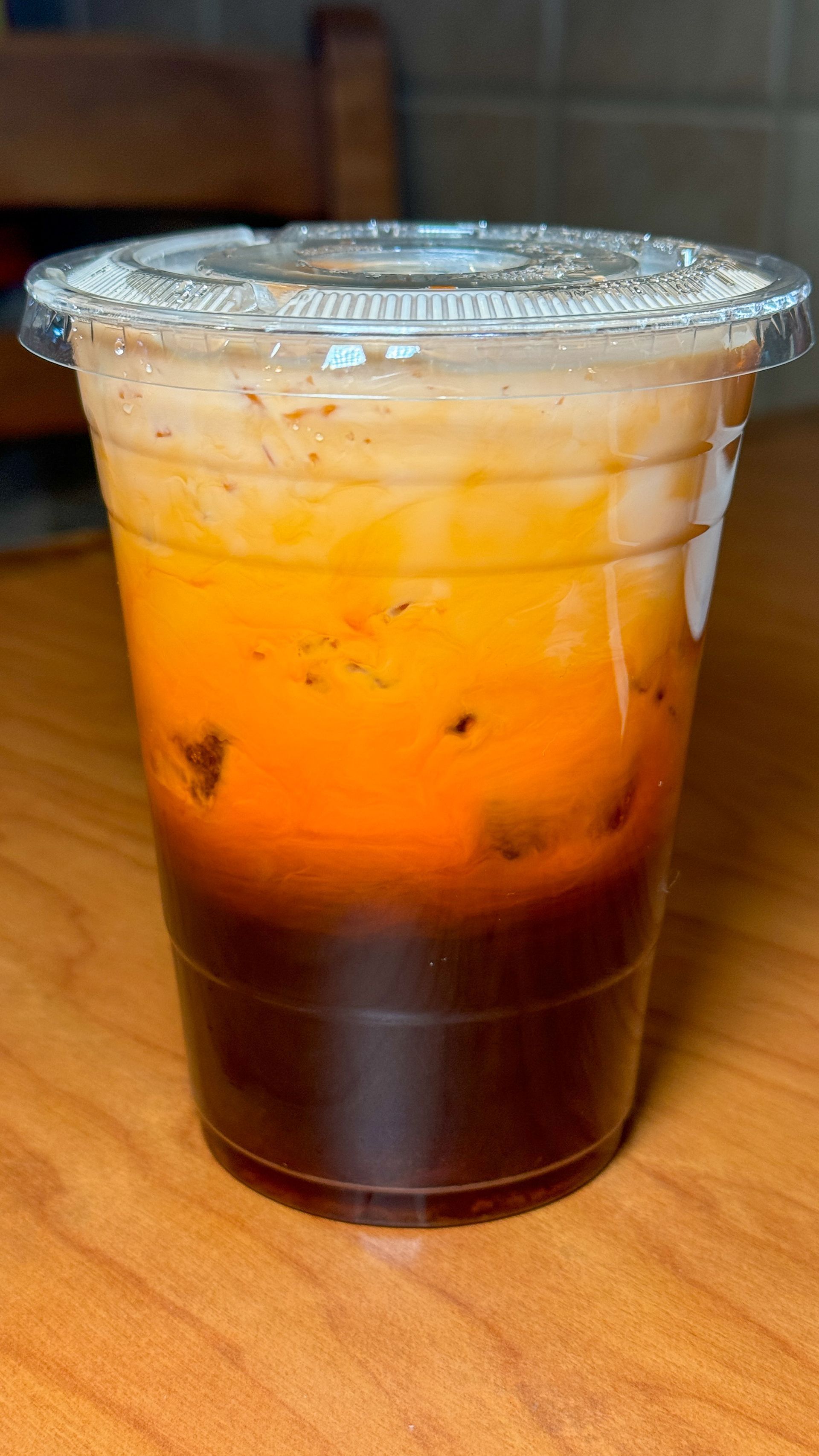 A cup of iced tea is sitting on a wooden table.