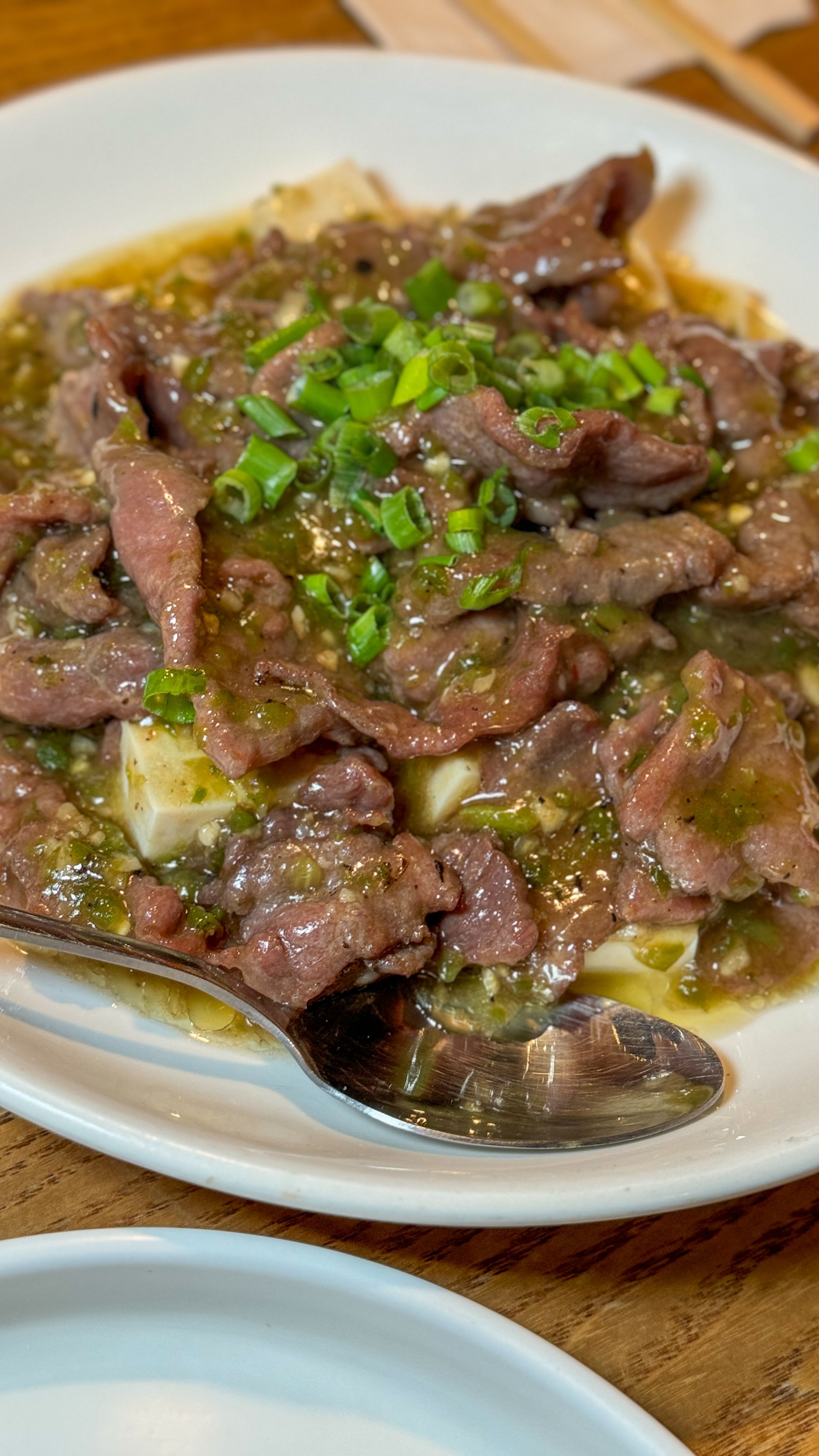 A close up of a plate of food with a spoon on a table.