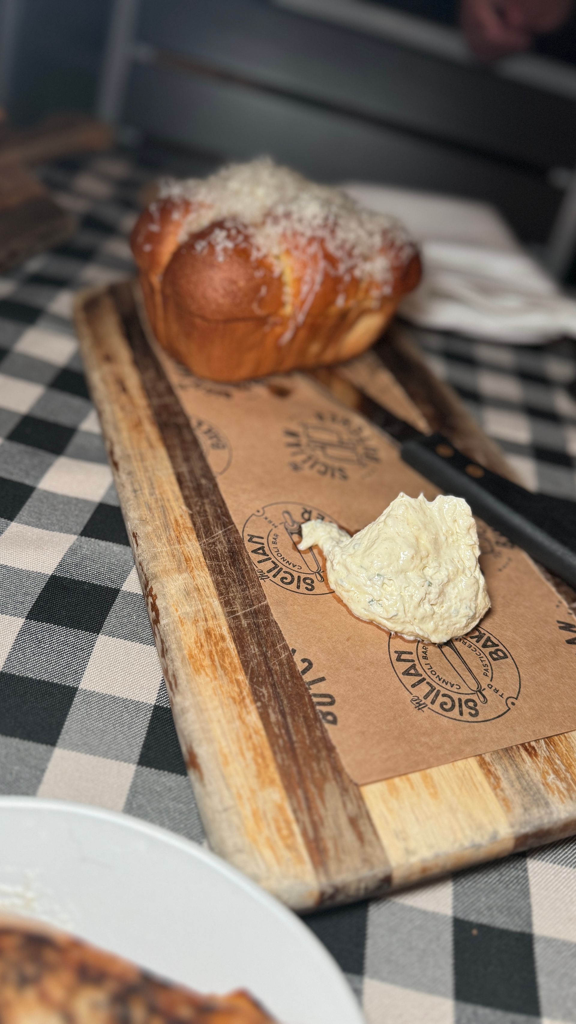 A wooden cutting board with bread and butter on it on a table.