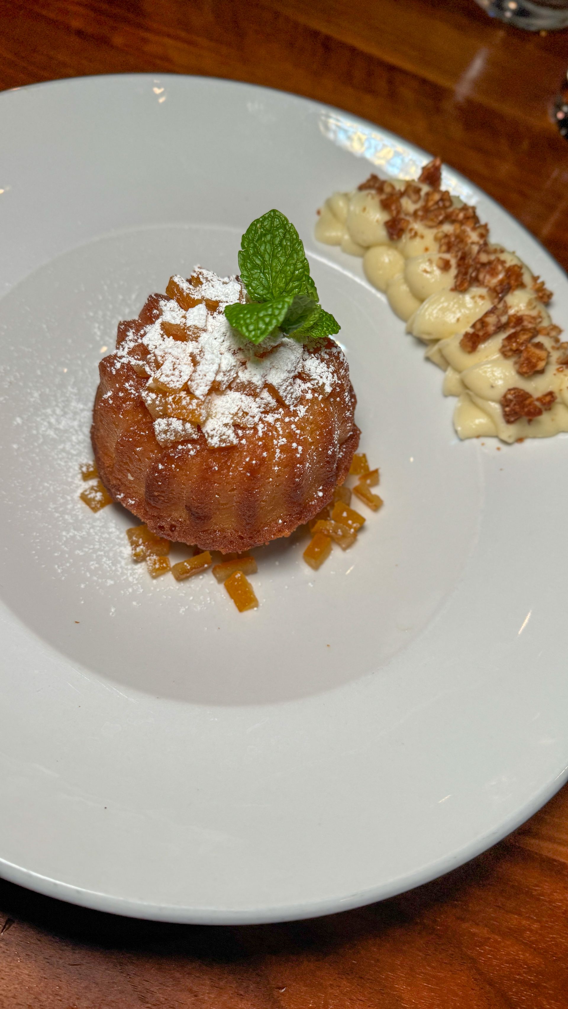 A white plate topped with a dessert and powdered sugar on a wooden table.