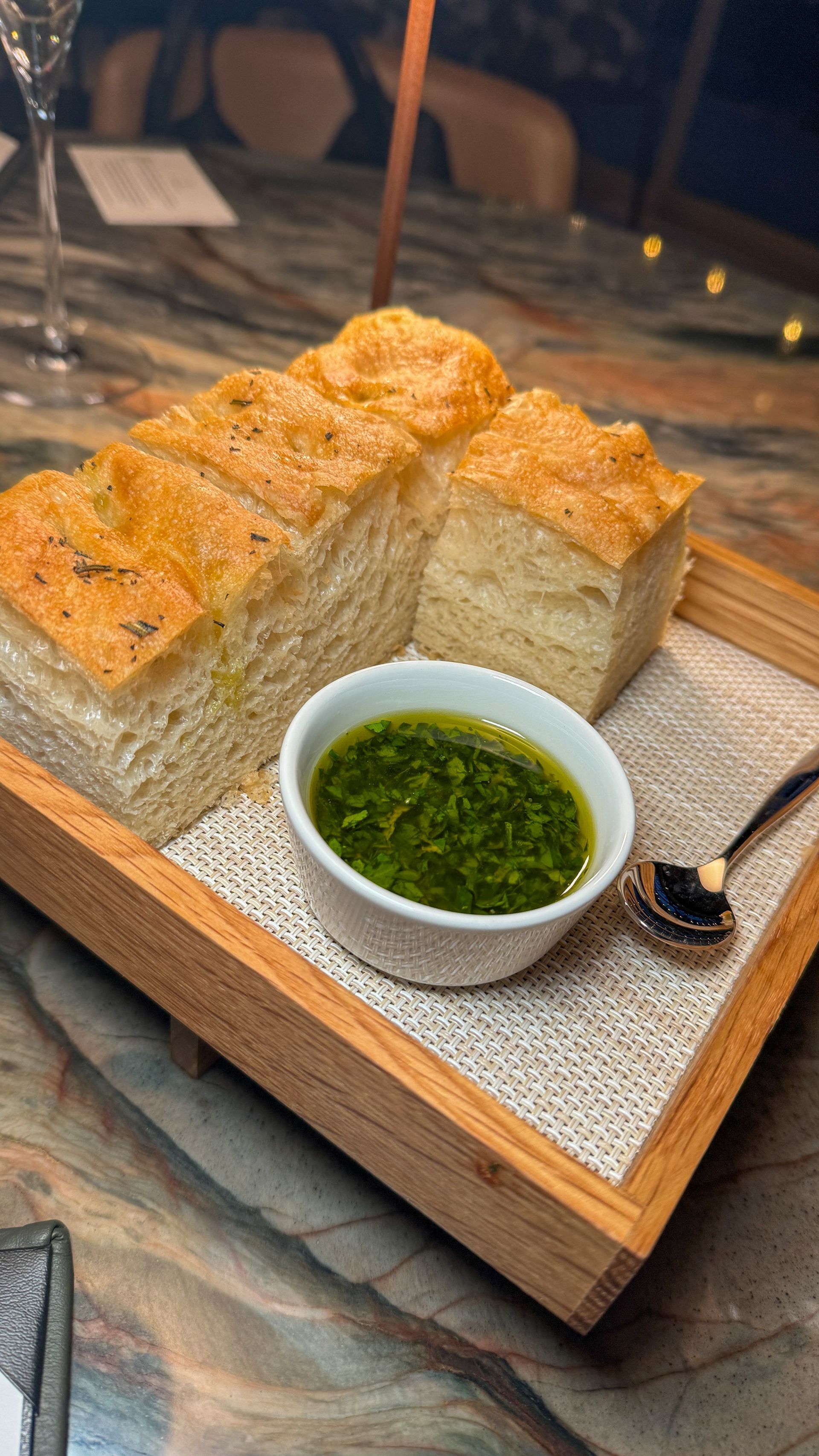 A wooden tray with bread and a bowl of sauce on it.