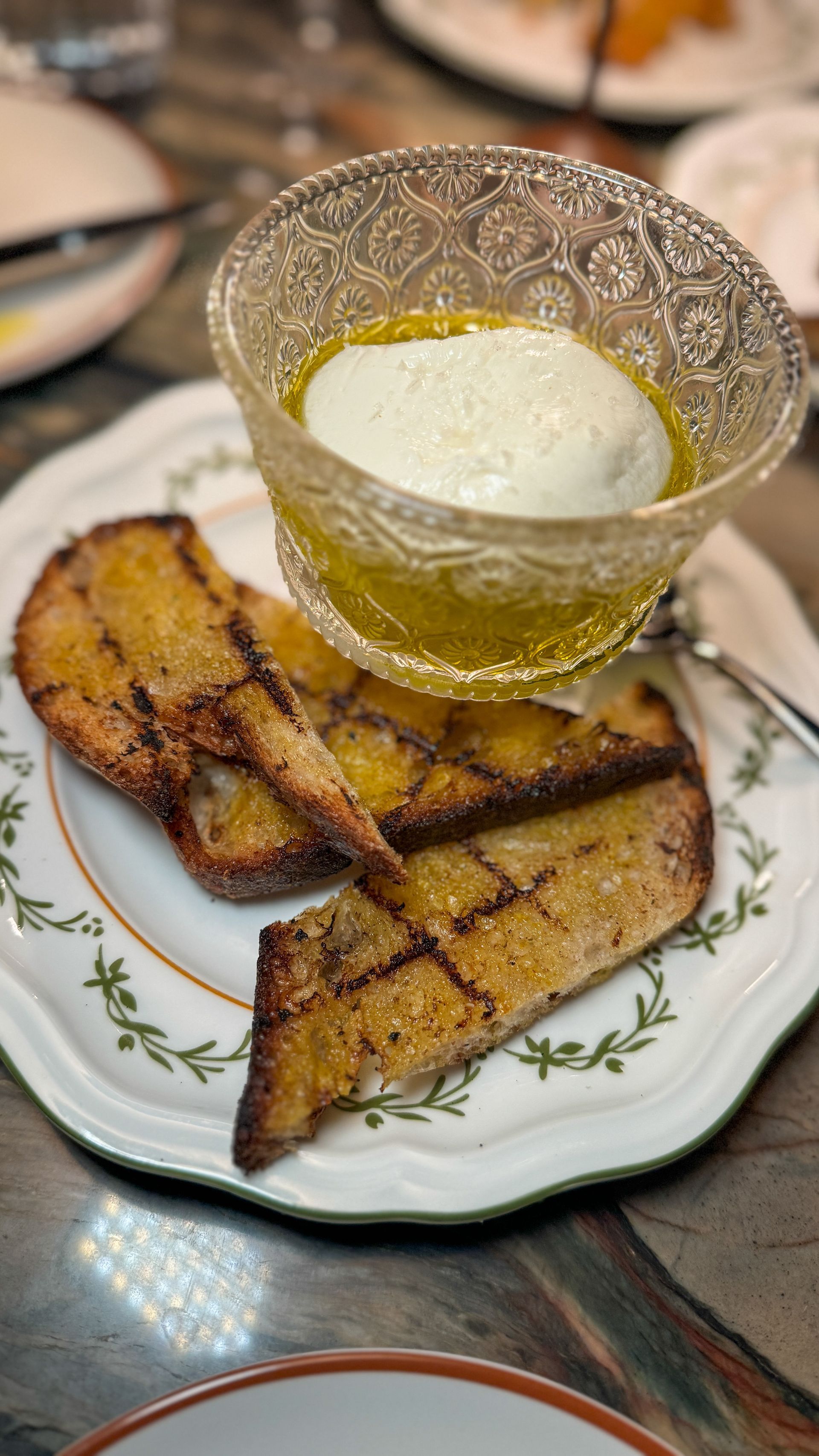 A plate of food with bread and a bowl of yogurt on a table.