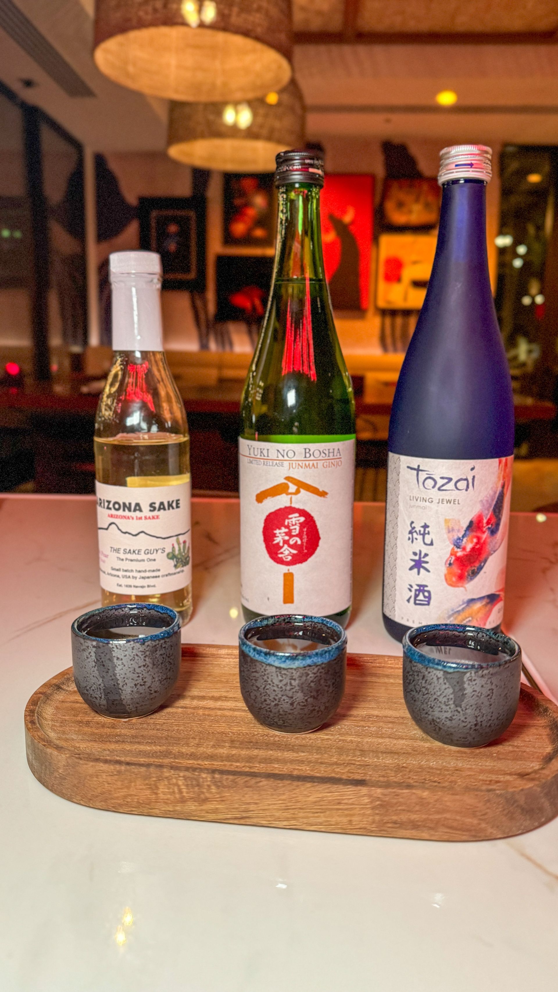 Three bottles of alcohol are sitting on a wooden tray on a table.