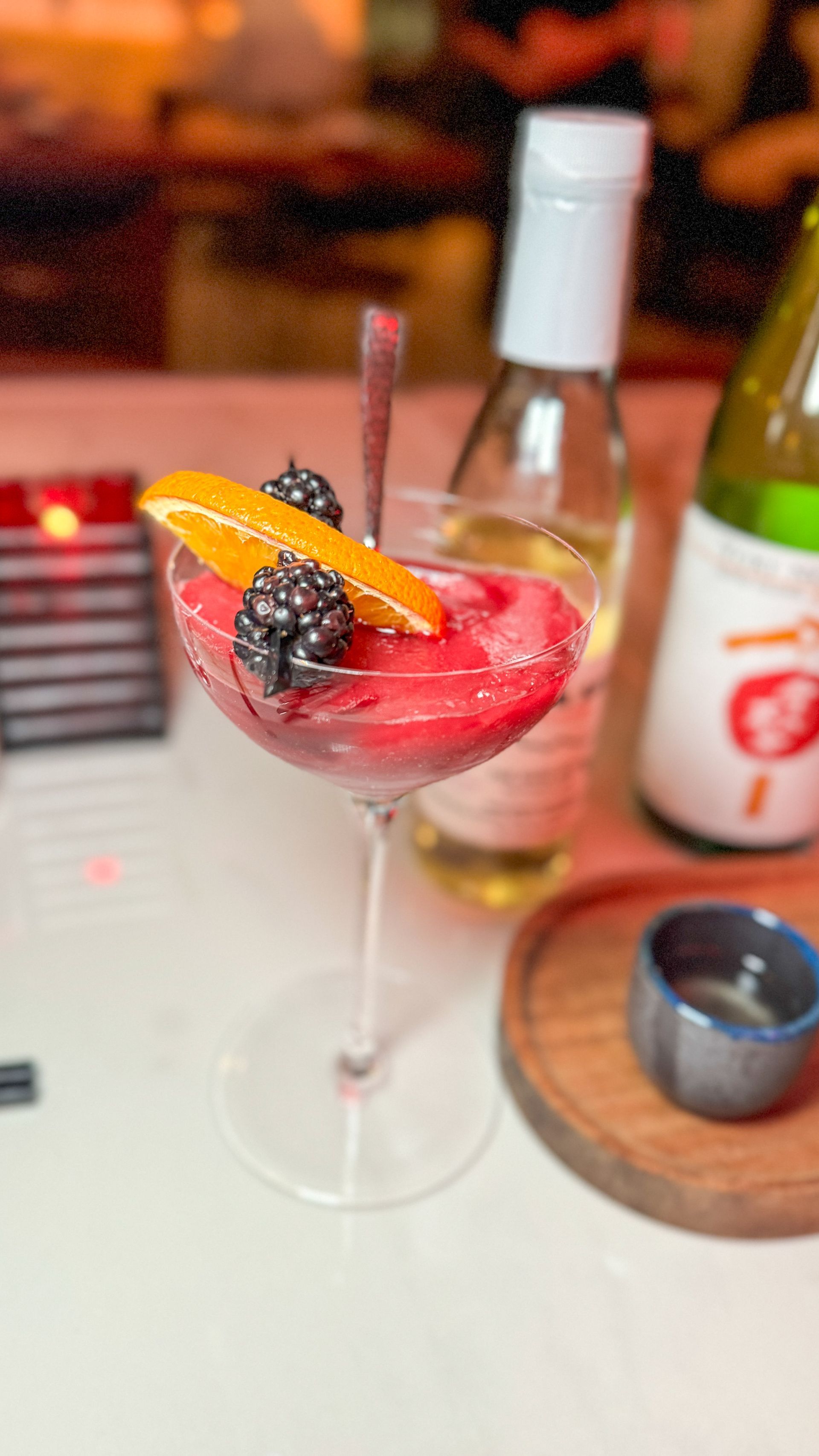 A close up of a martini with berries and orange slices on a table.