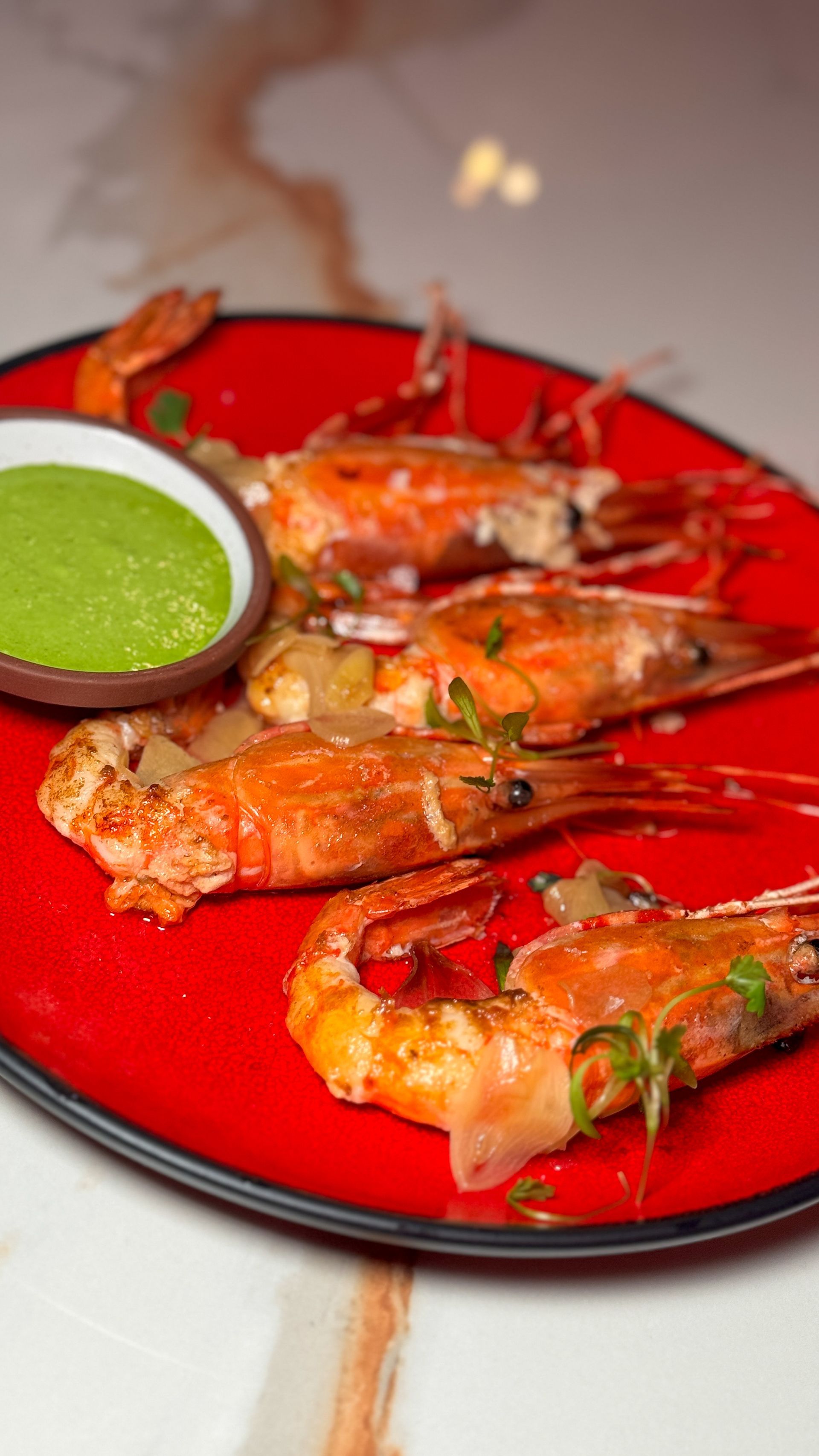 A close up of a plate of shrimp with sauce on a table.