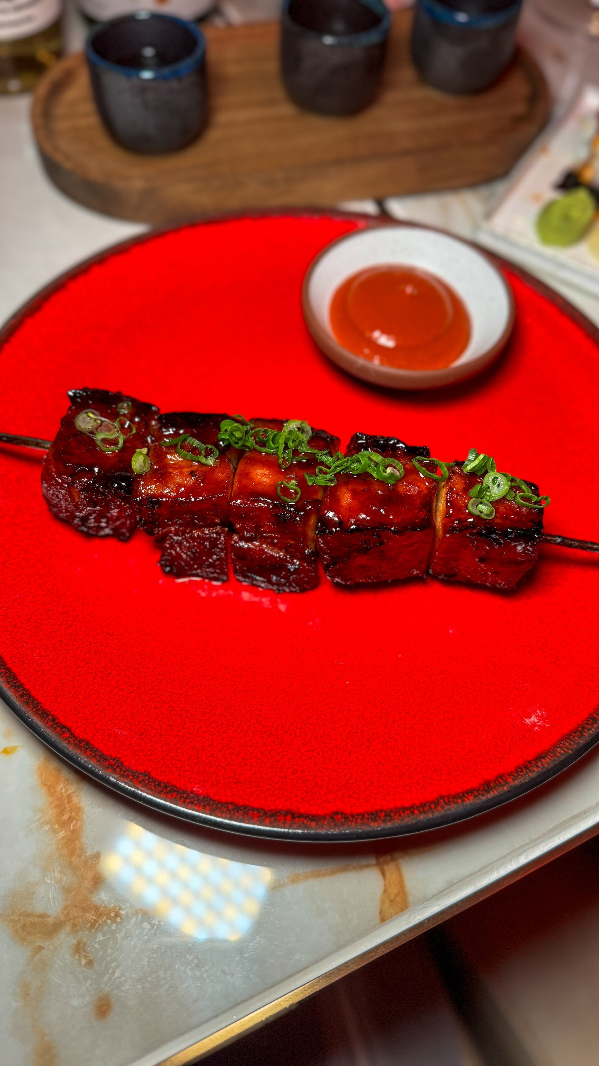 A red plate topped with meat and sauce on a table.