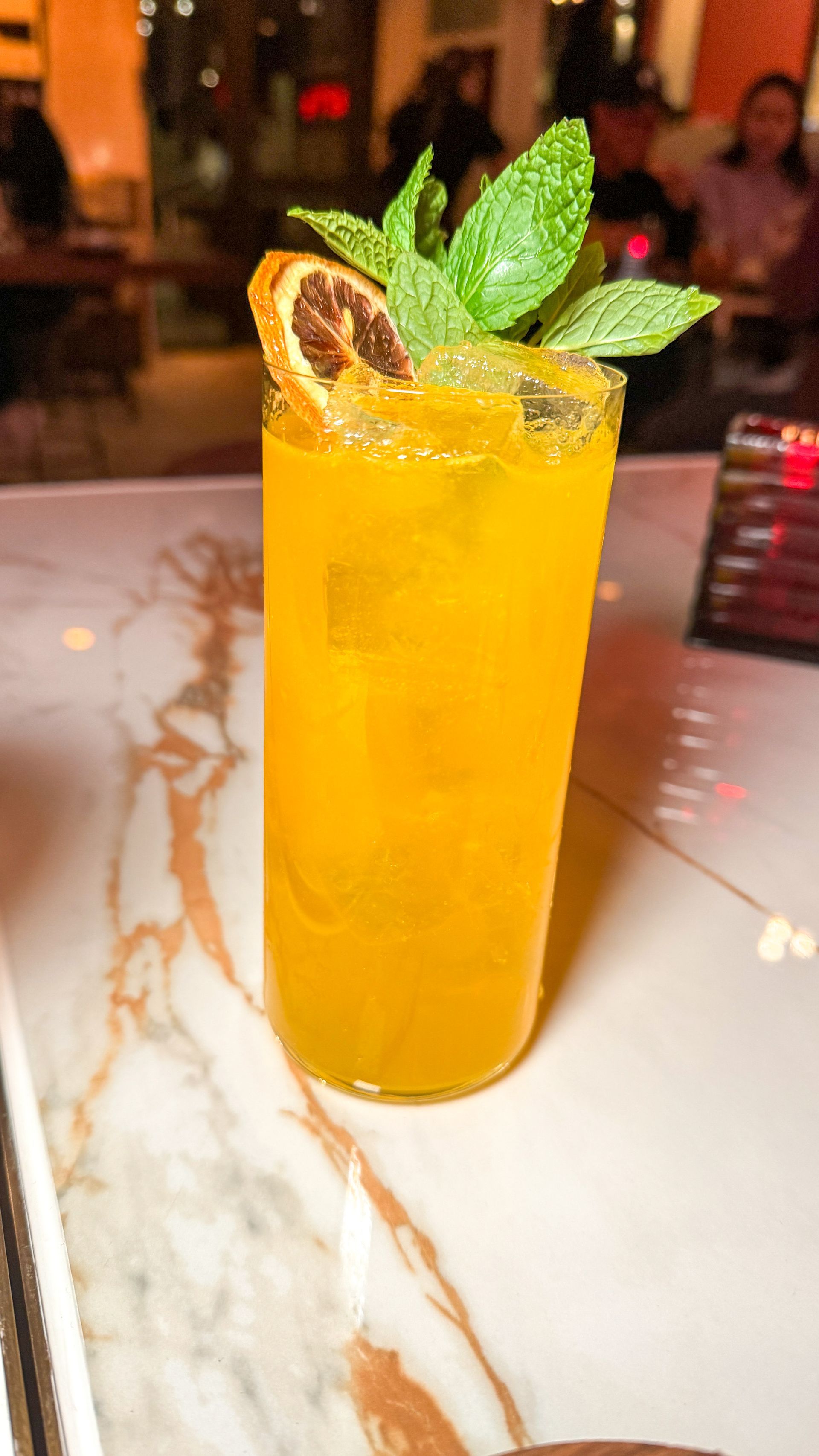 A close up of a drink in a tall glass on a table.