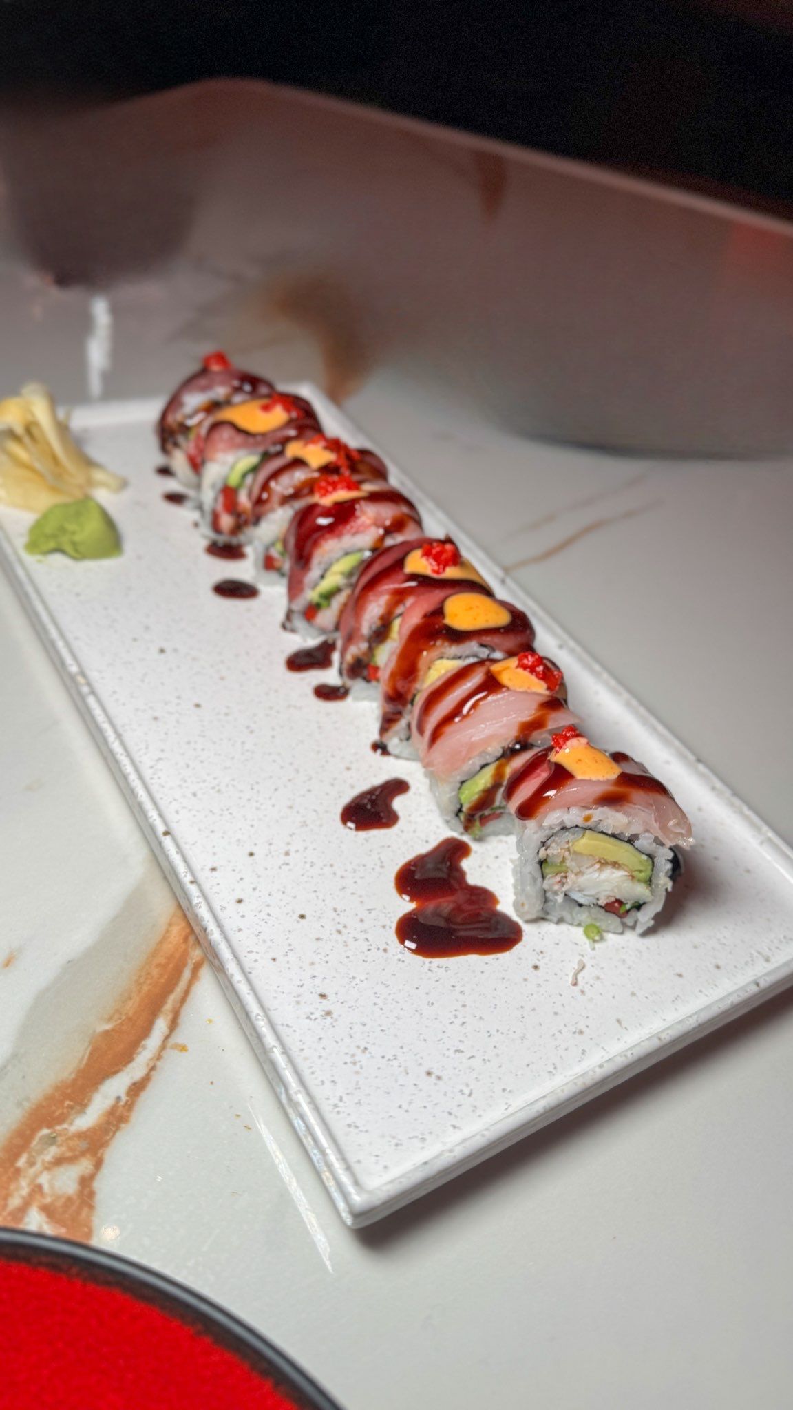 A row of sushi rolls on a white plate on a table.