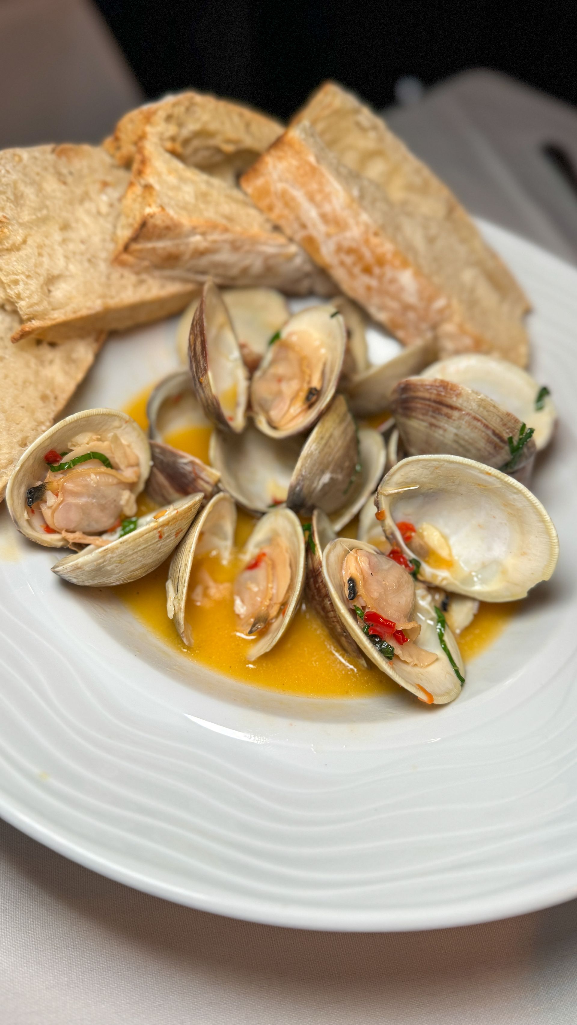 A white plate topped with clams and bread on a table.