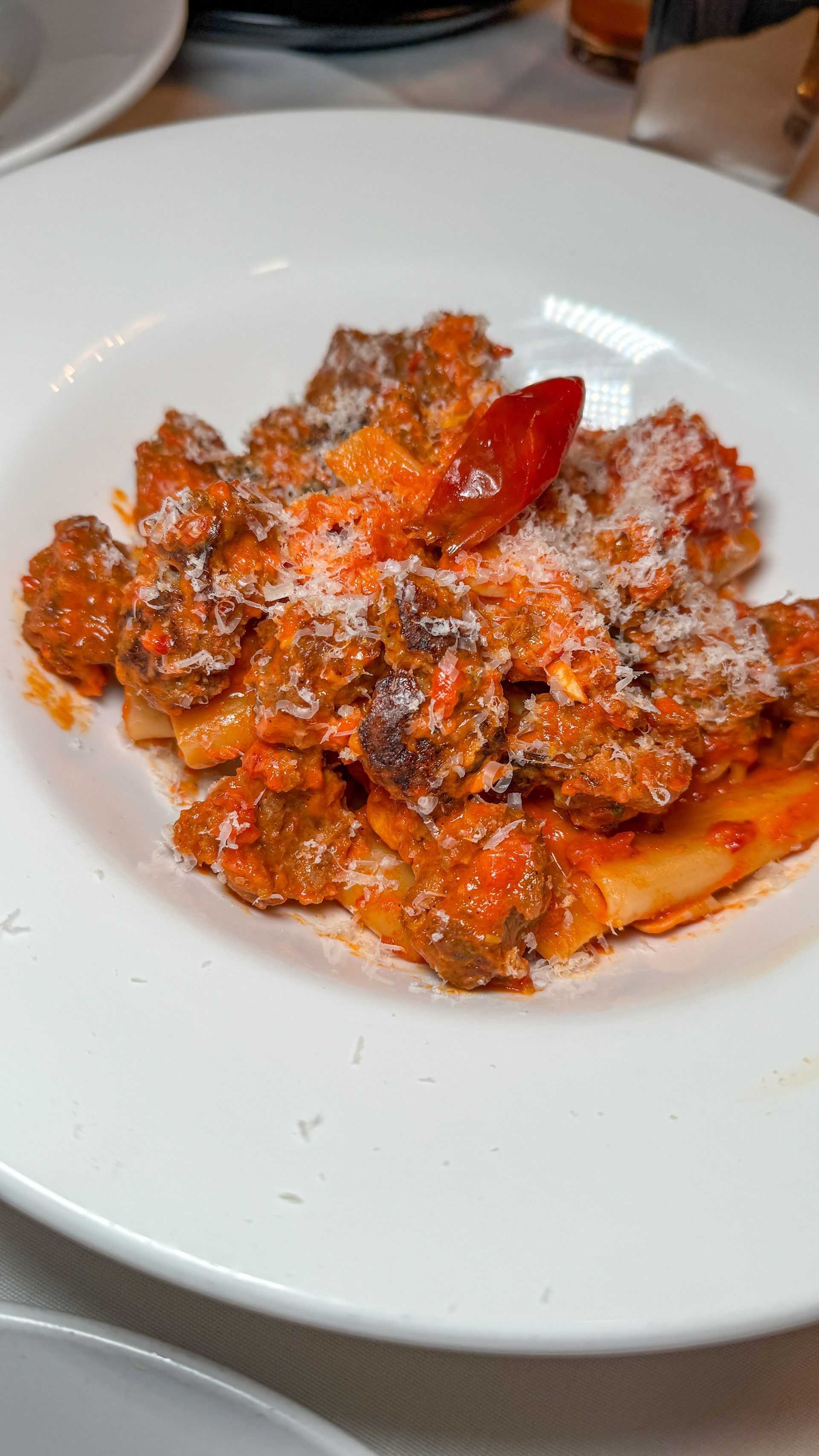 A close up of a plate of pasta with meat and sauce on a table.