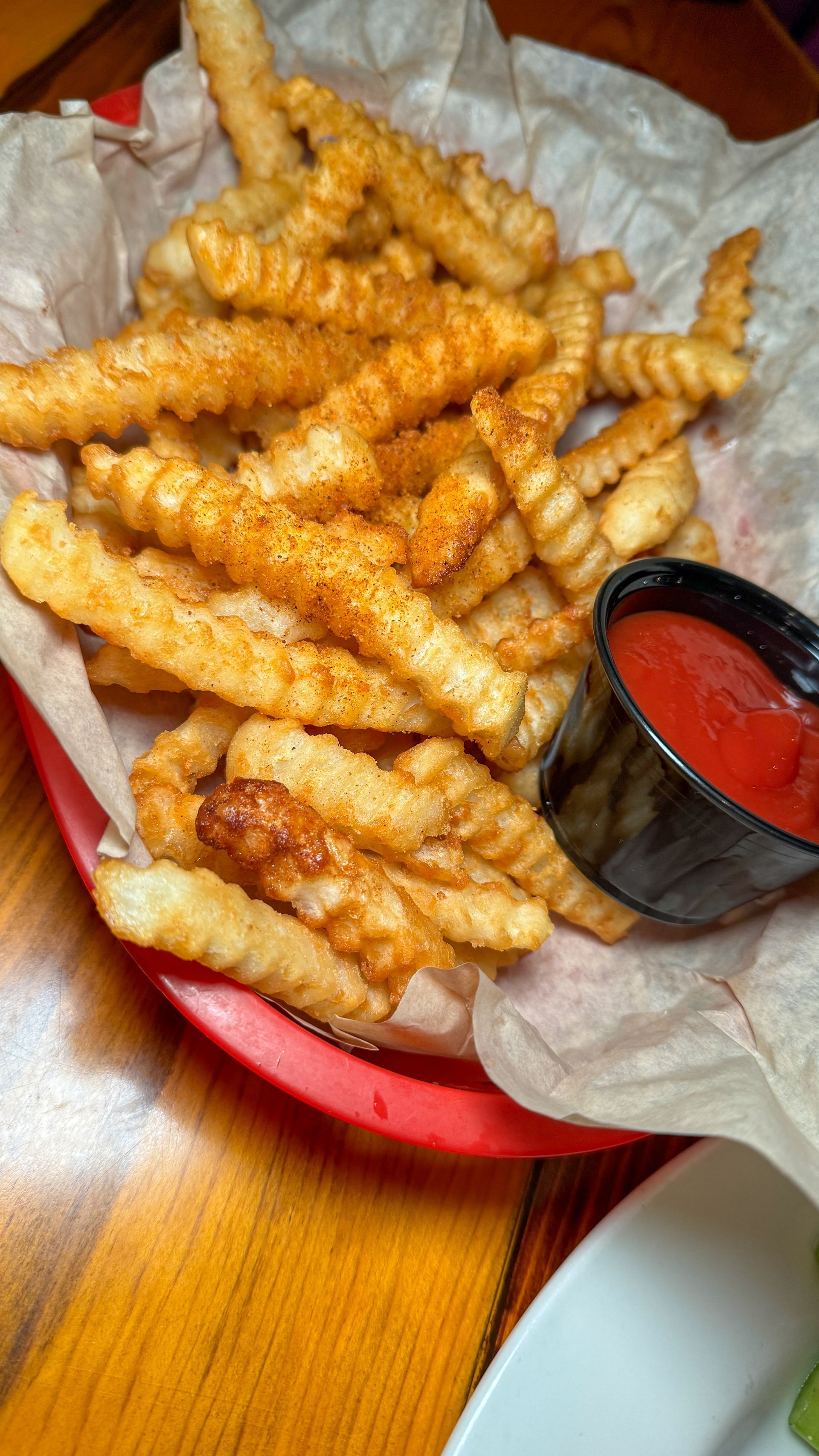 A basket of french fries with ketchup on a wooden table.