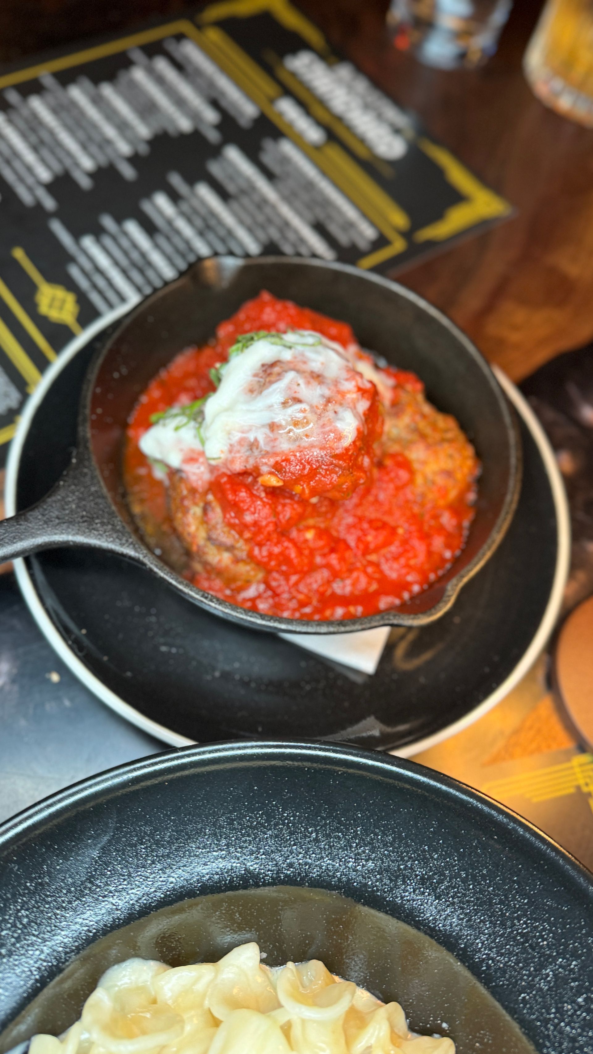 A close up of a plate of food with meatballs and sauce on a table.
