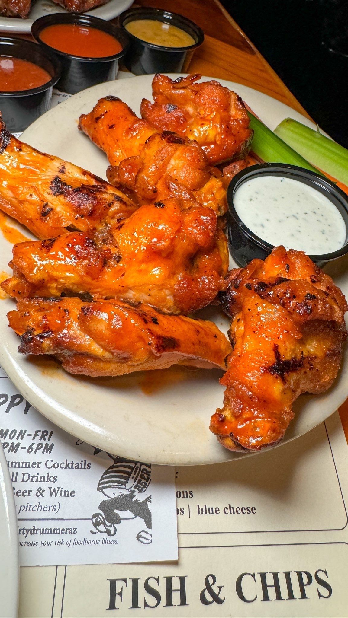 A plate of chicken wings with ranch dressing and celery on a table.