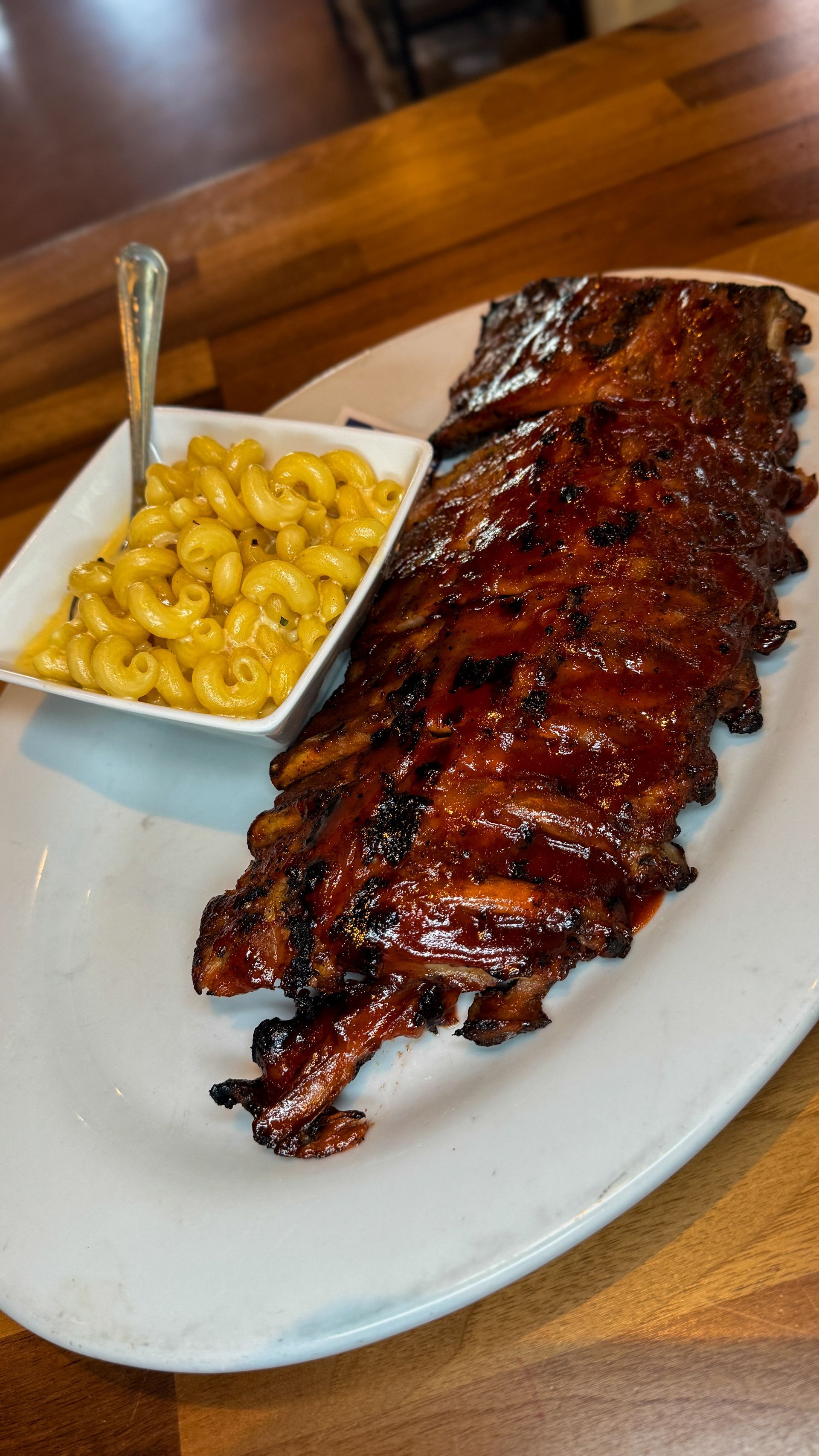 Rack of glazed ribs with mac and cheese on a white plate.