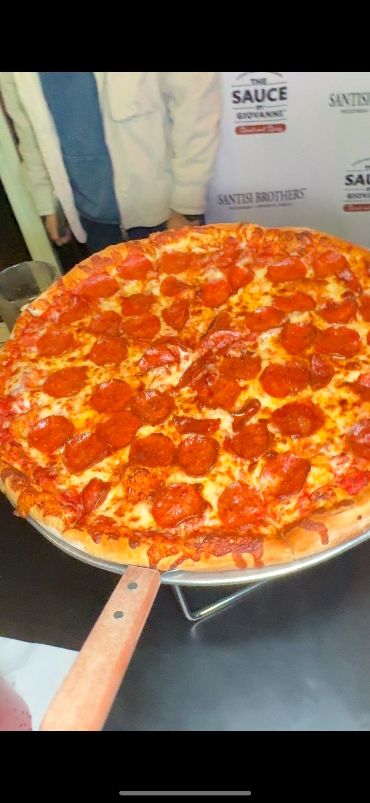 A pepperoni pizza is sitting on a pan on a table.