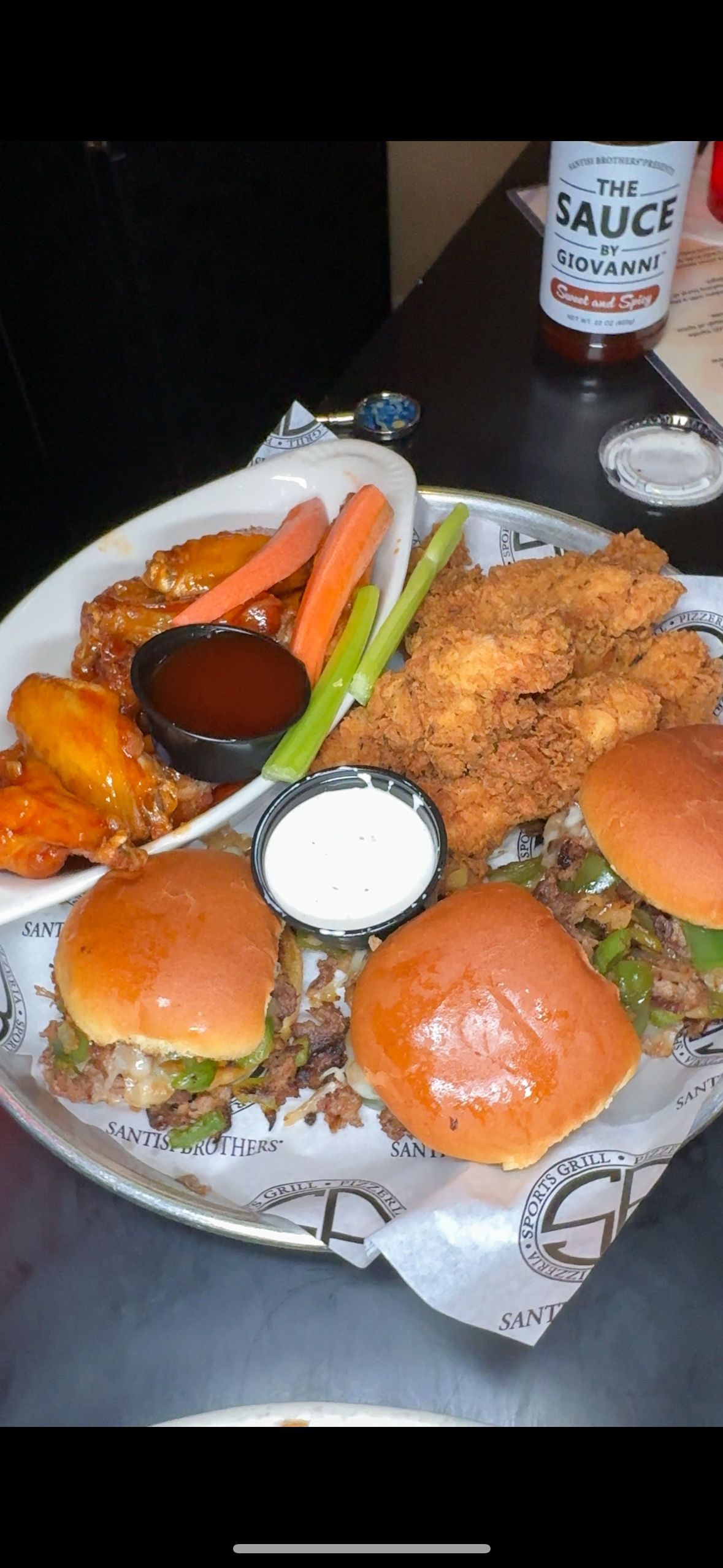 A plate of food with a bottle of sauce in the background.