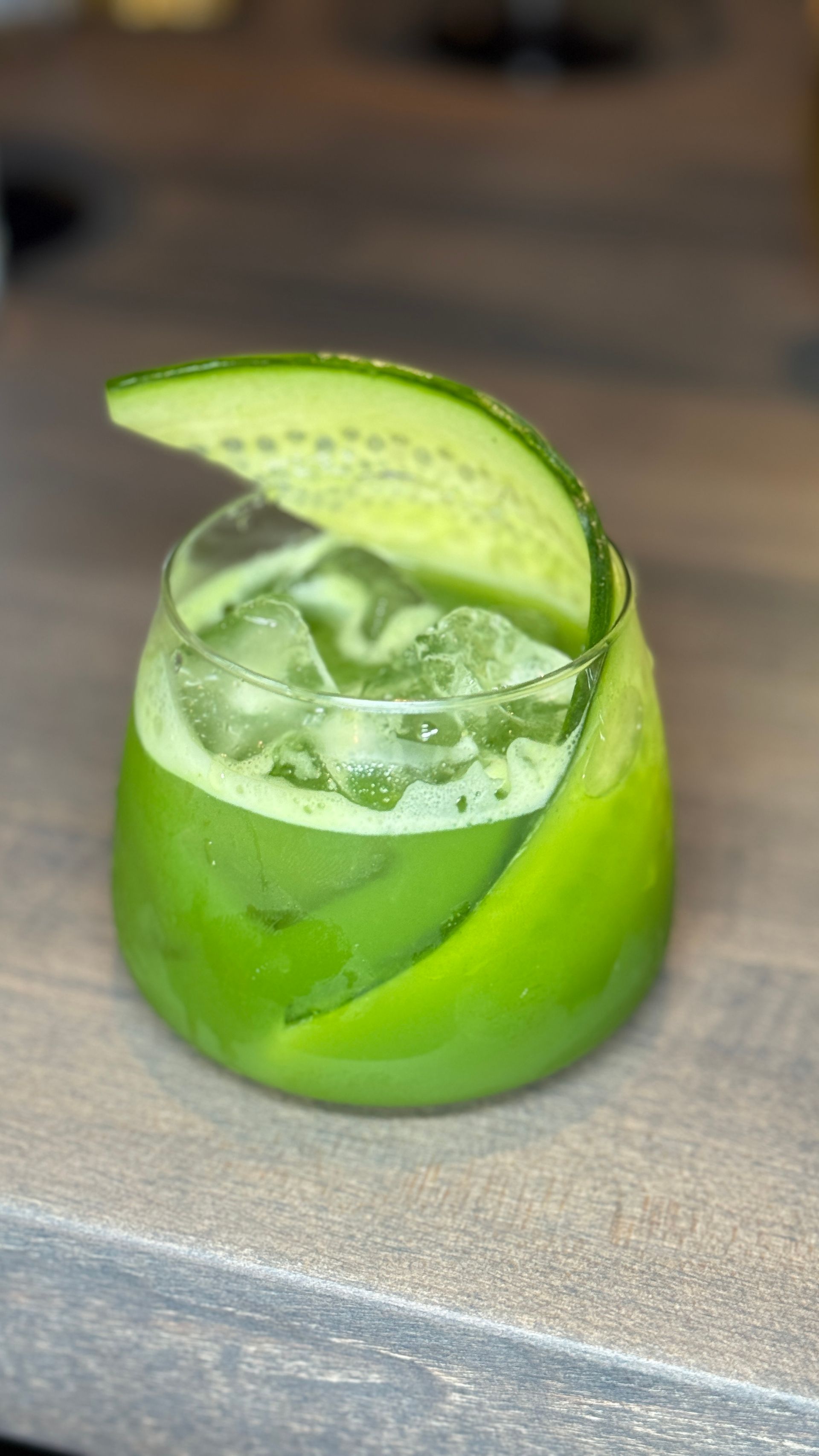 A close up of a green drink in a glass on a table.