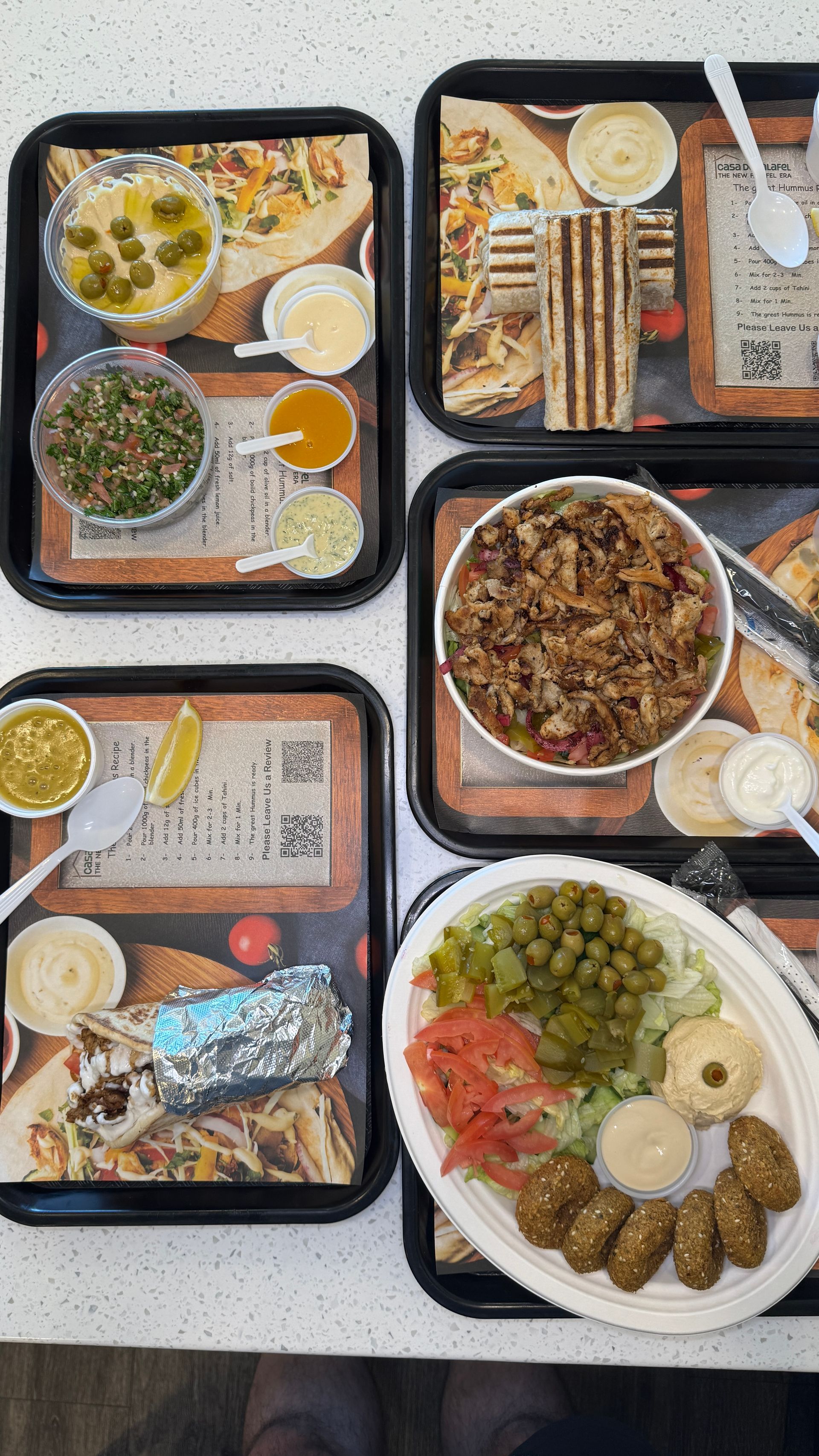 Several trays of Middle Eastern food with dips, pita, and falafel.