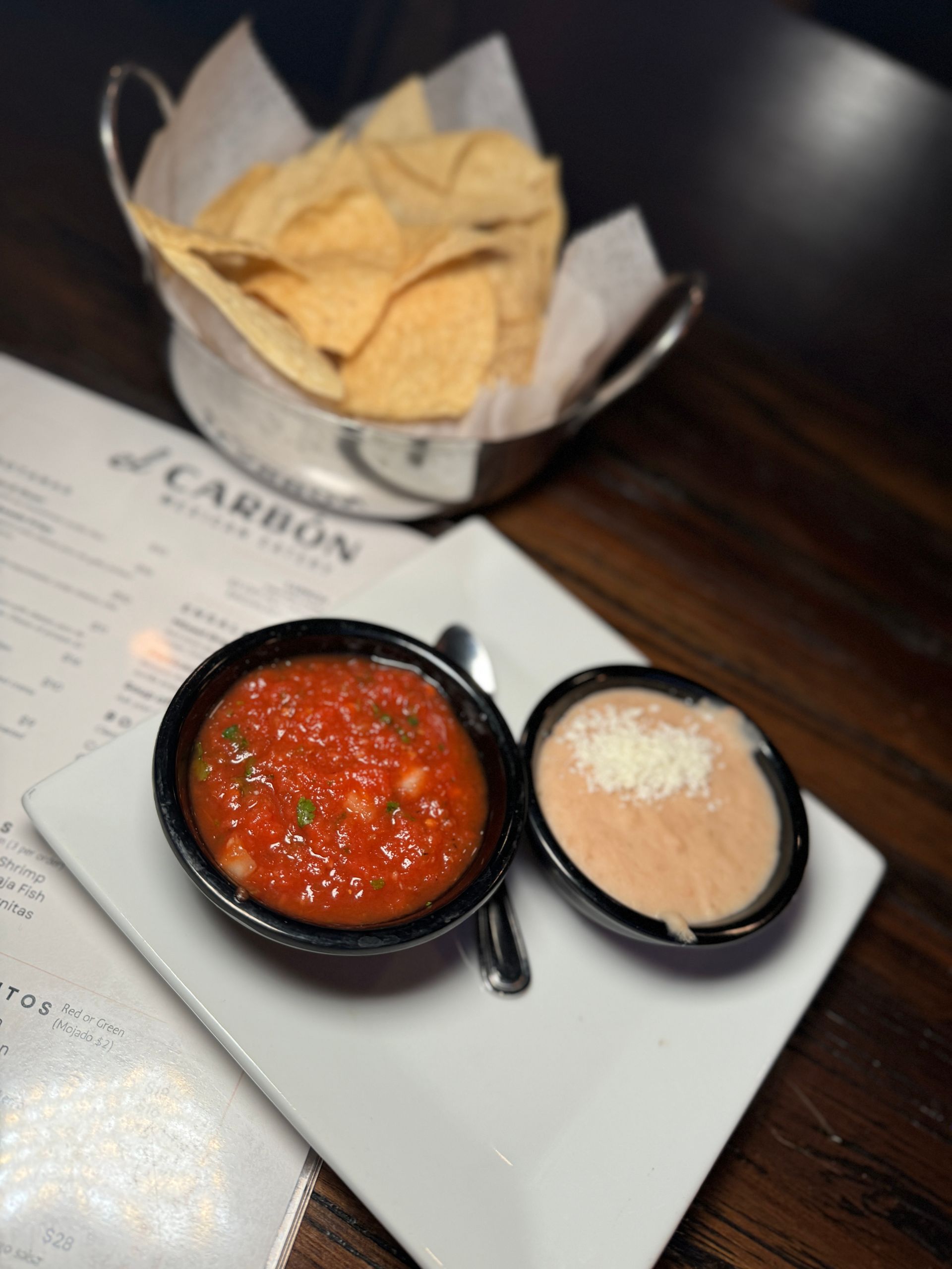 A bowl of salsa and a bowl of chips on a plate
