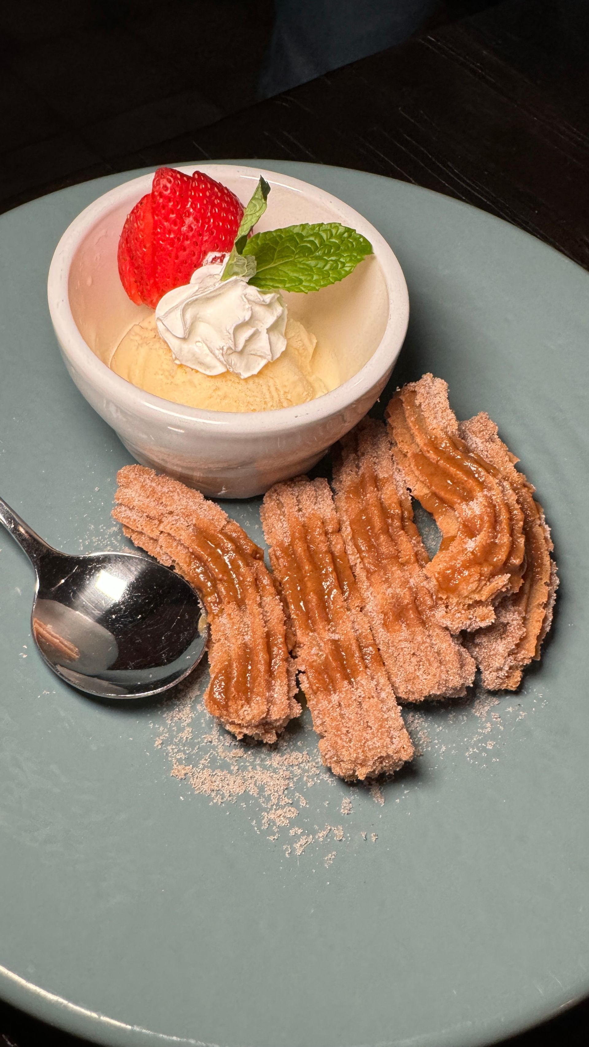 A plate of churros with a bowl of ice cream and a strawberry on top.
