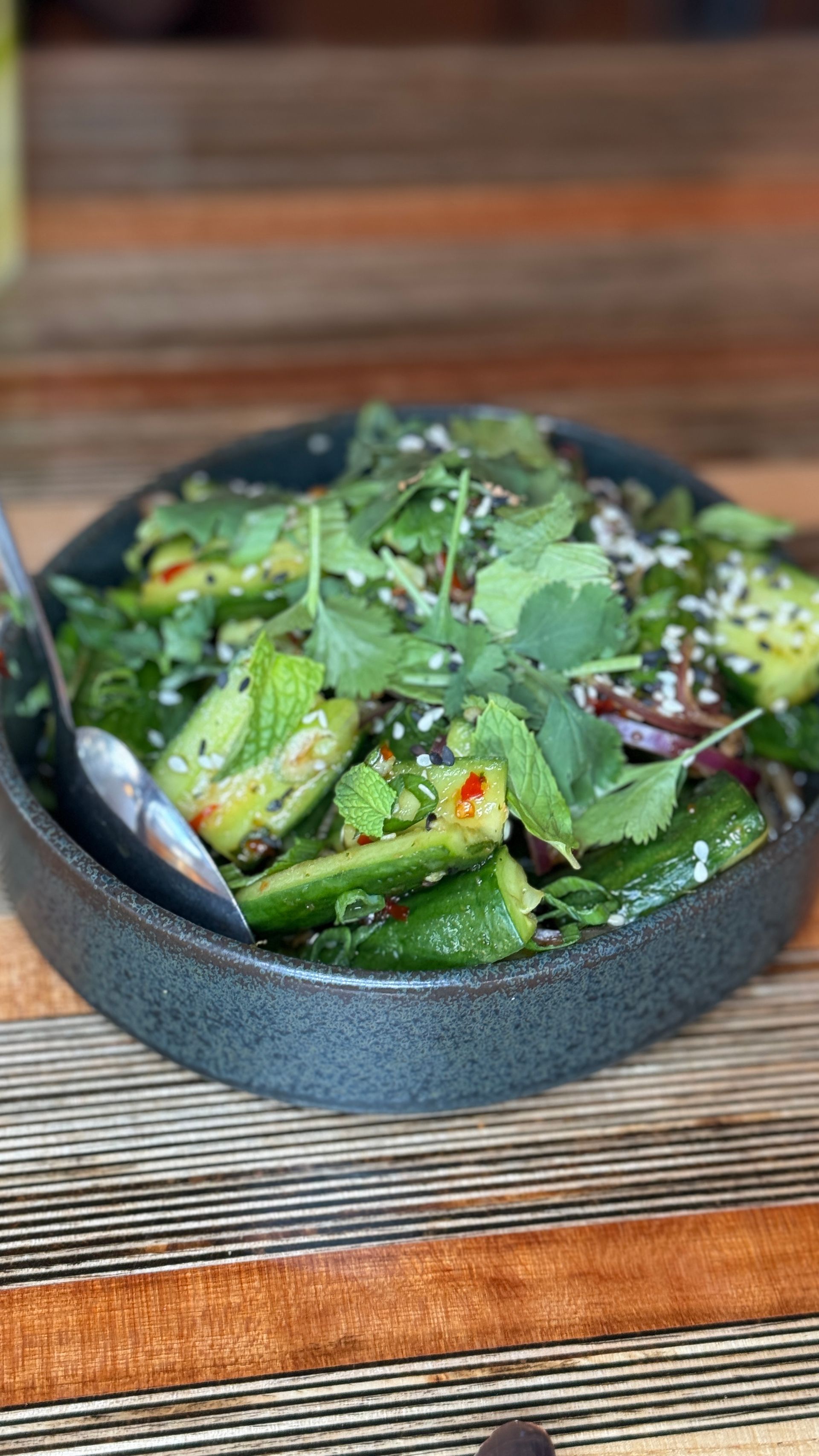 A bowl of food with a spoon in it is sitting on a wooden table.