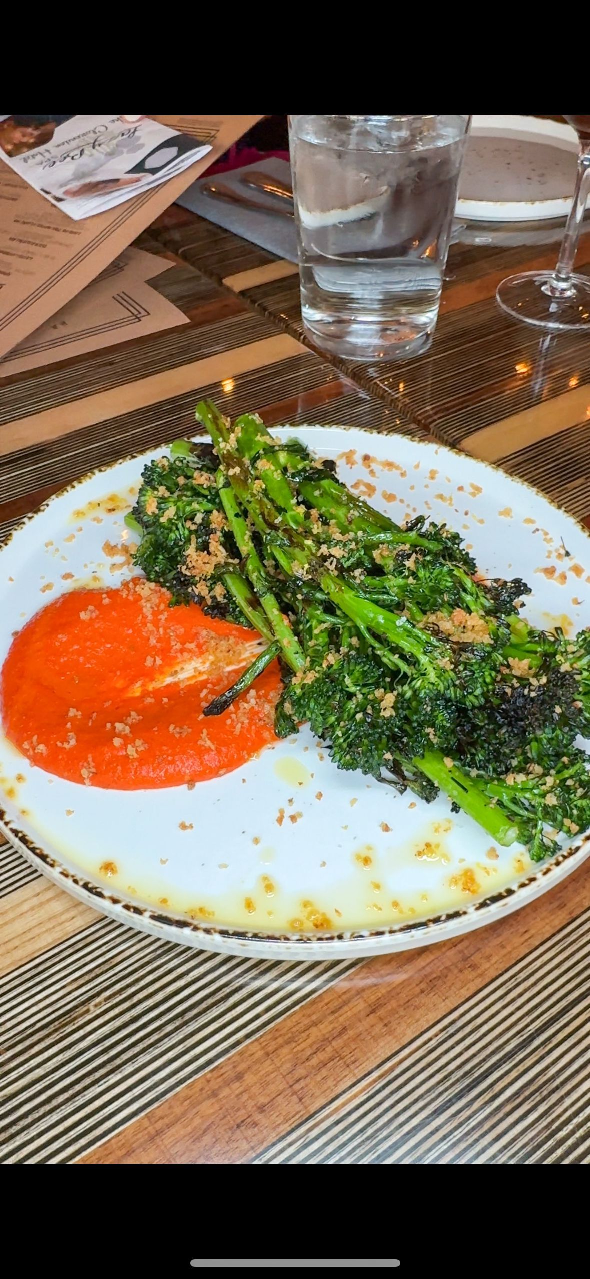 A plate of food with broccoli and sauce on a table.