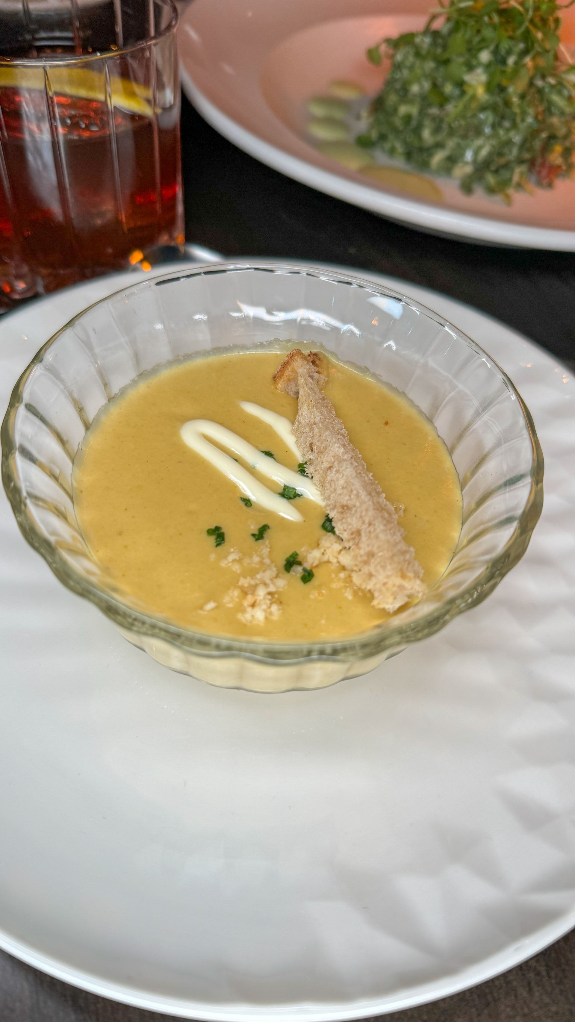 A bowl of soup with a piece of bread on a plate.