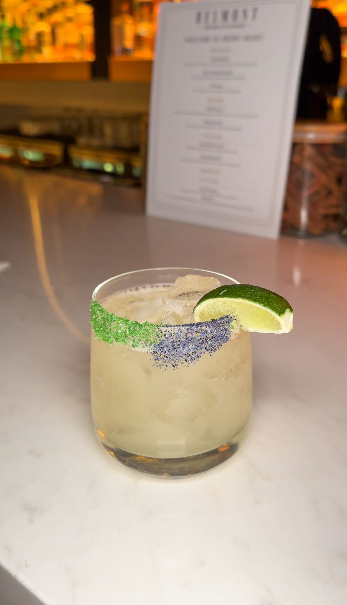 A close up of a margarita with a slice of lime on a table.