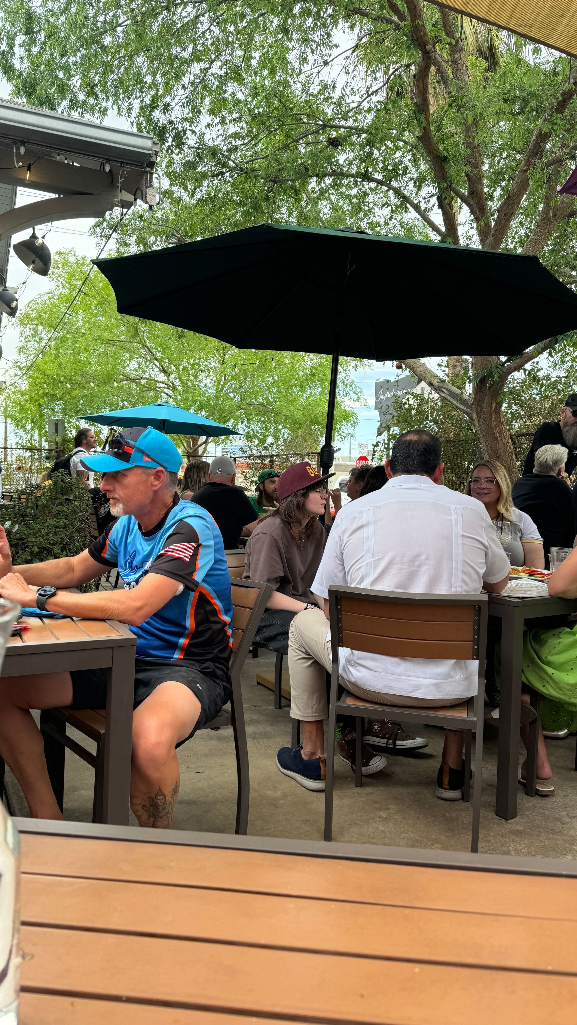 A group of people are sitting at tables under umbrellas at a restaurant.