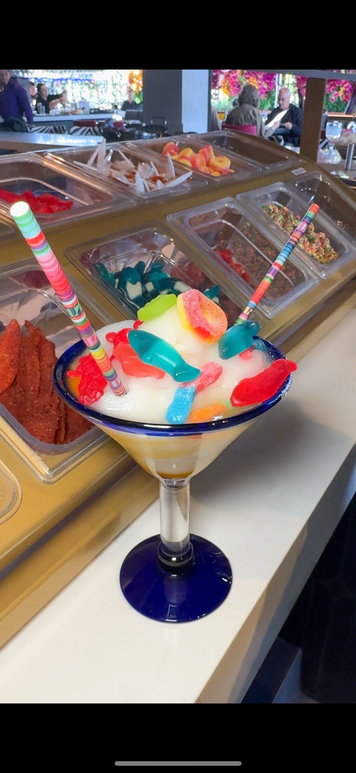 A martini glass filled with ice cream and candy on a table.