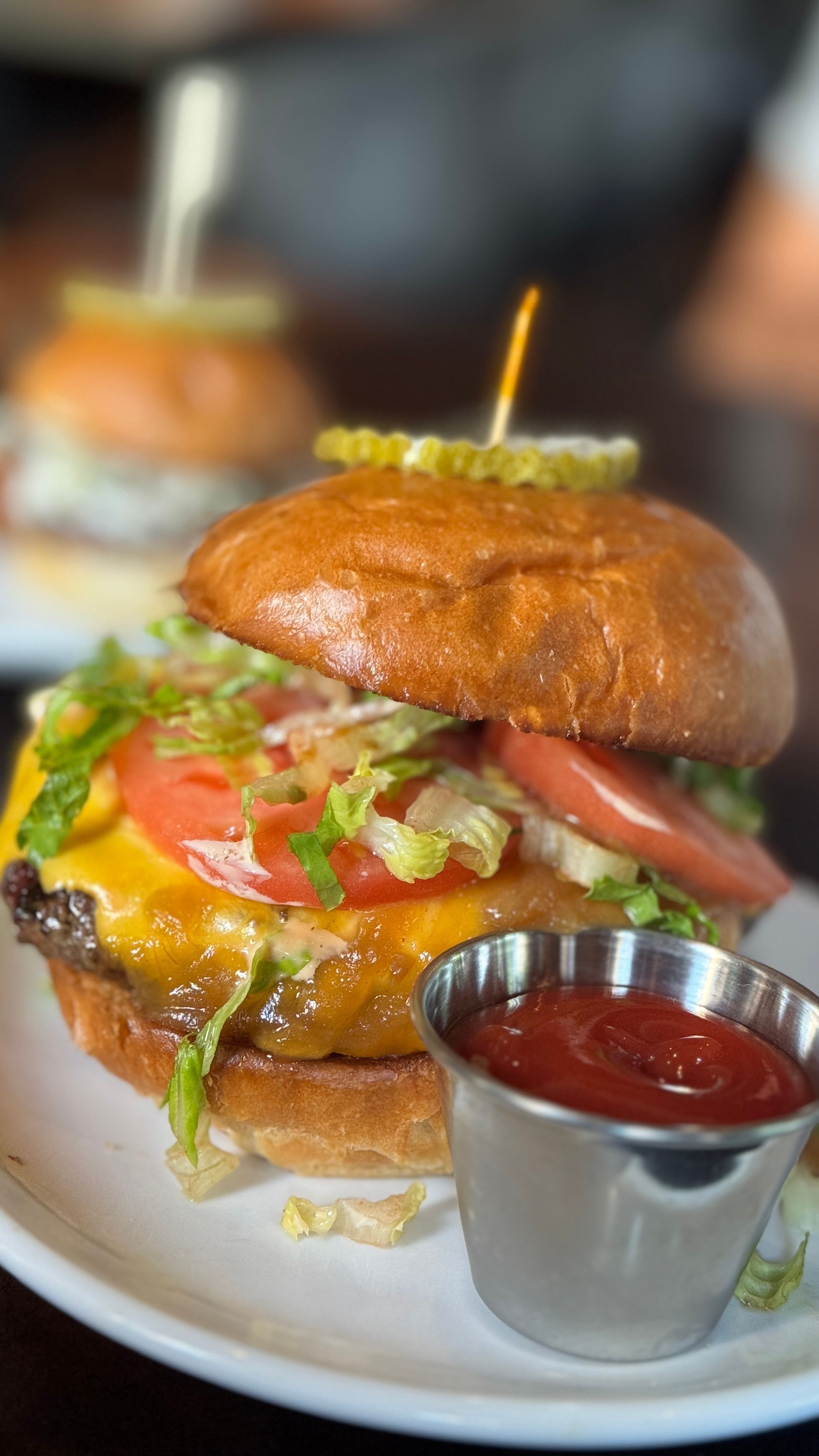 A close up of a hamburger on a plate with ketchup.