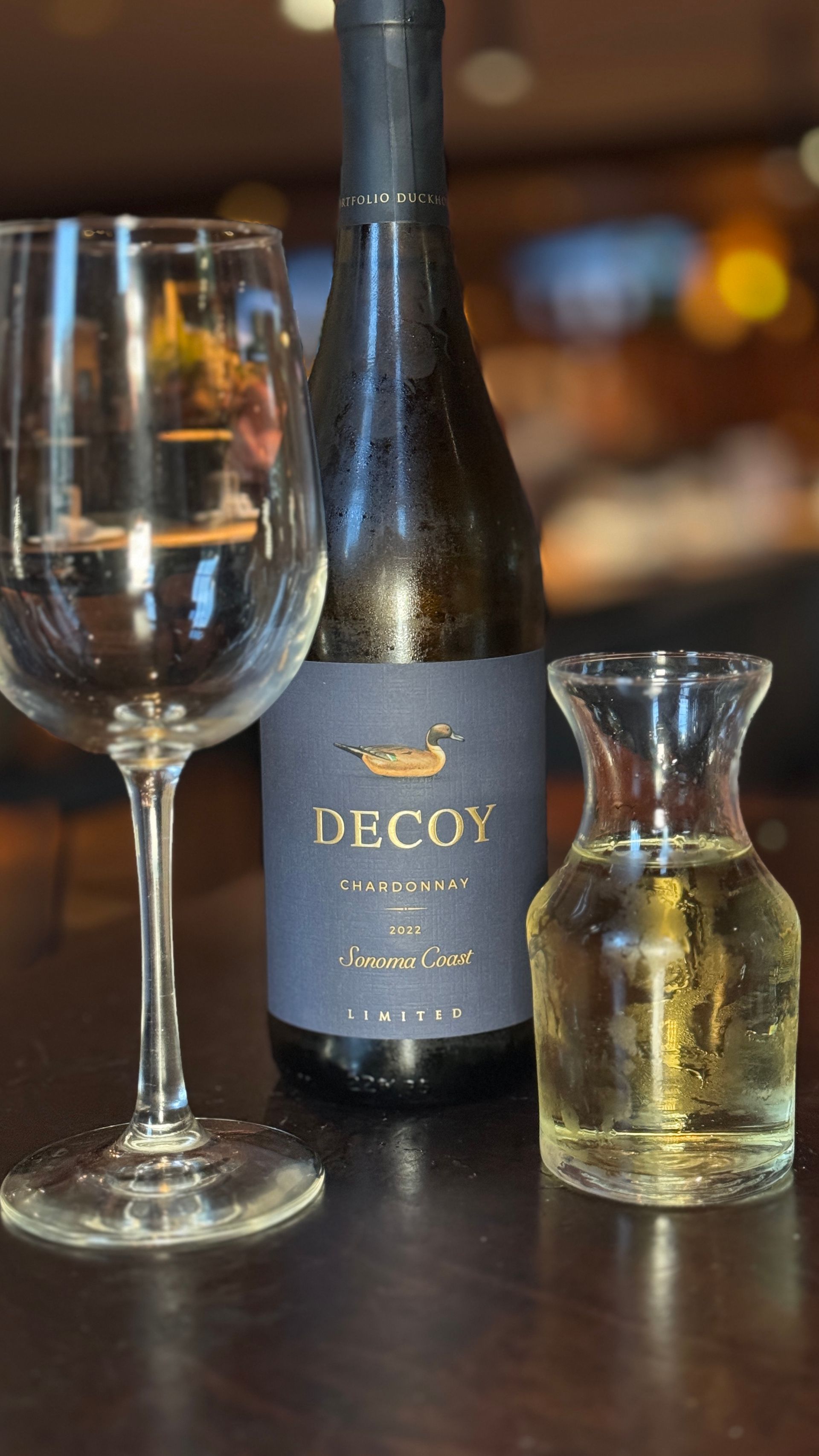 A bottle of decoy wine and a glass of wine are on a table.