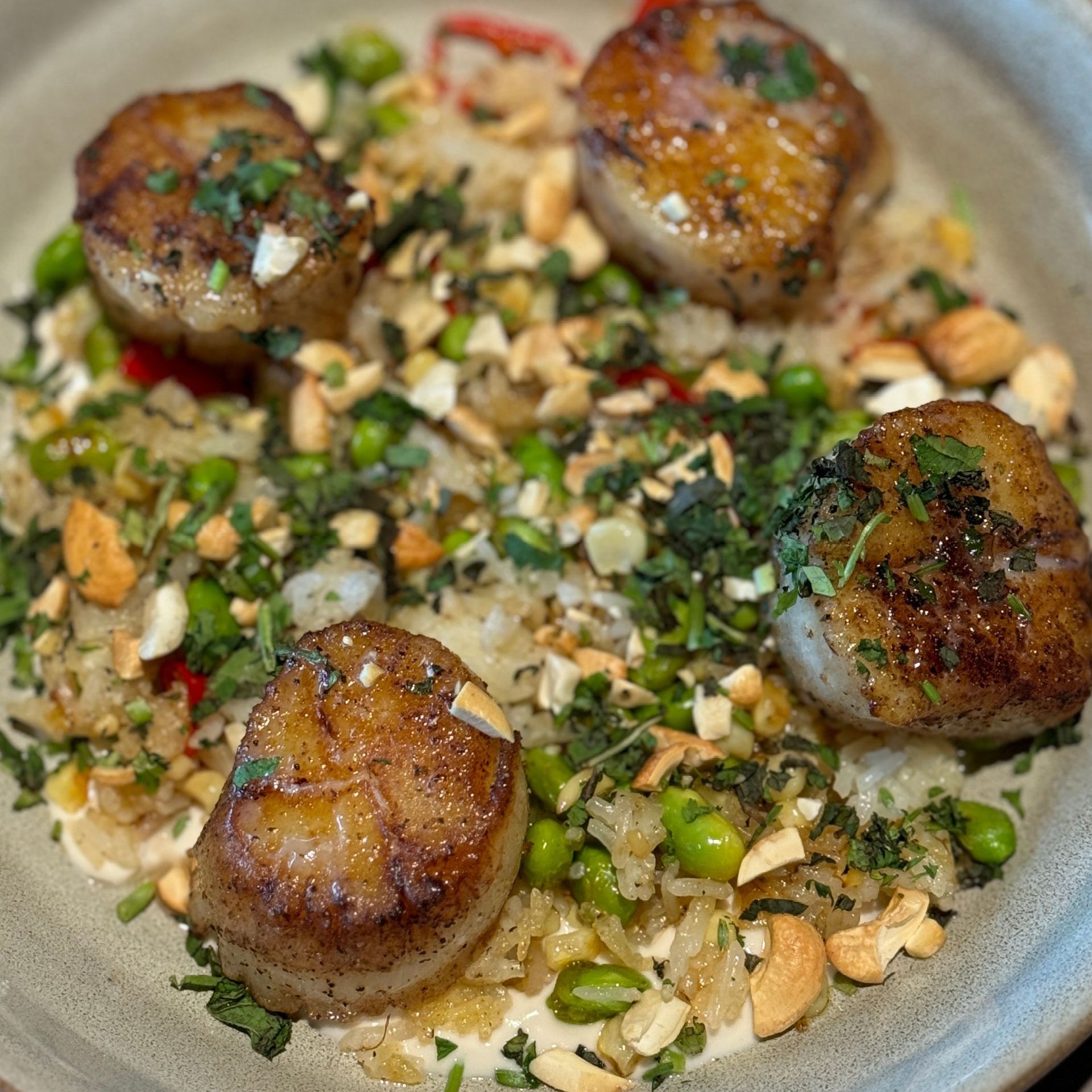 A close up of a plate of food with scallops and rice on a table.