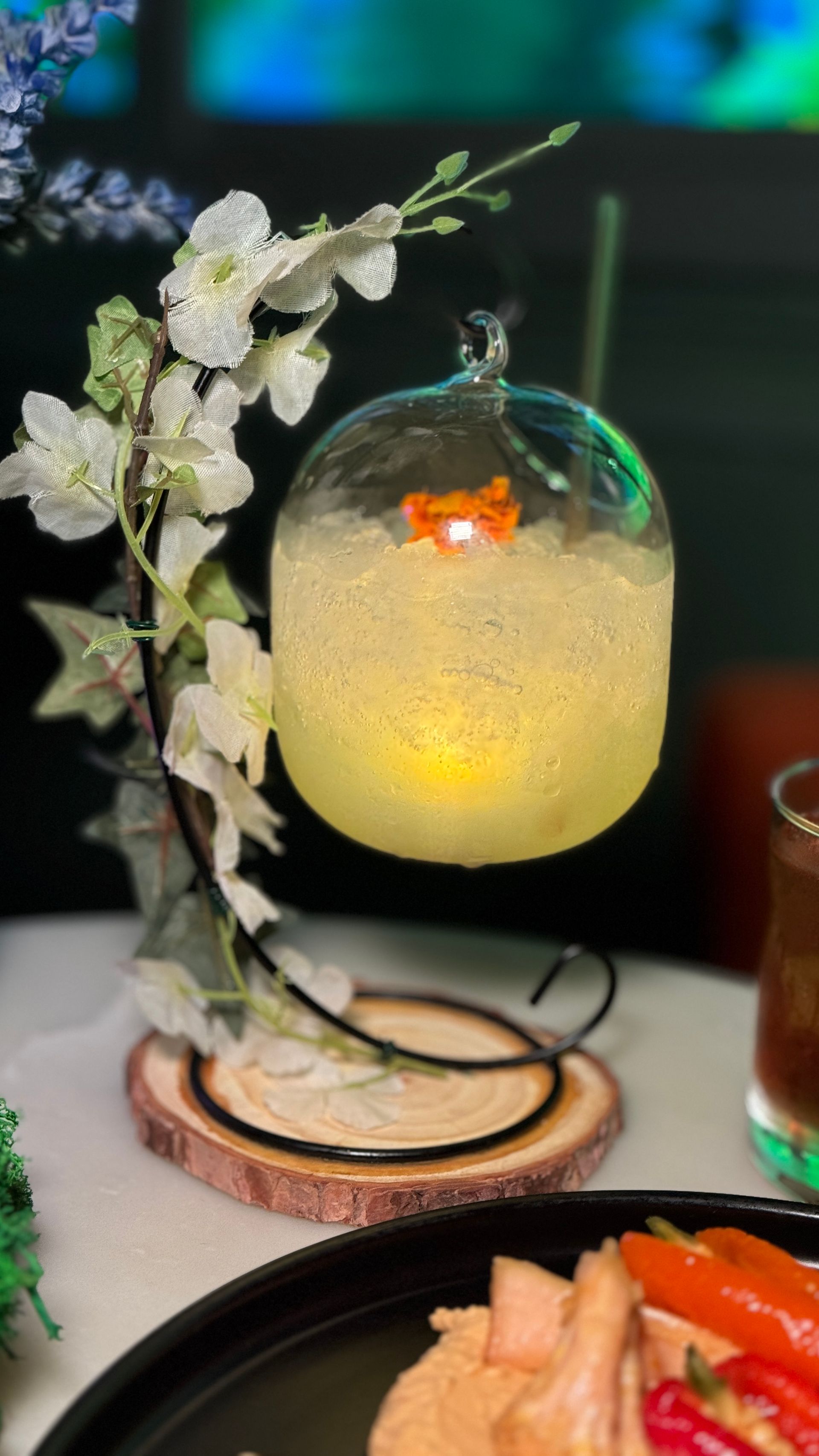 A glass with a fish in it is sitting on a table next to a plate of food.