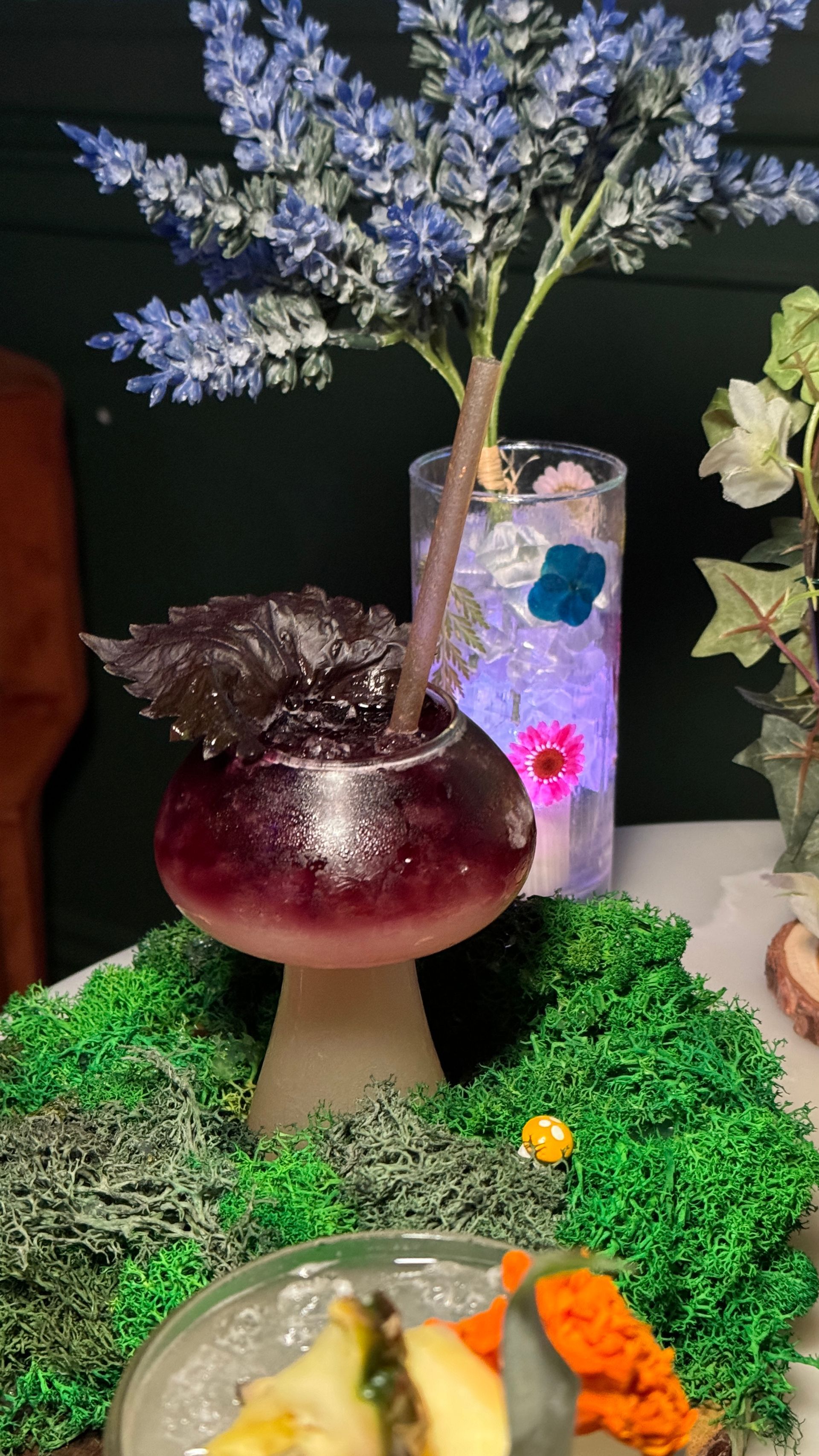 A mushroom filled with a drink and flowers on a table.