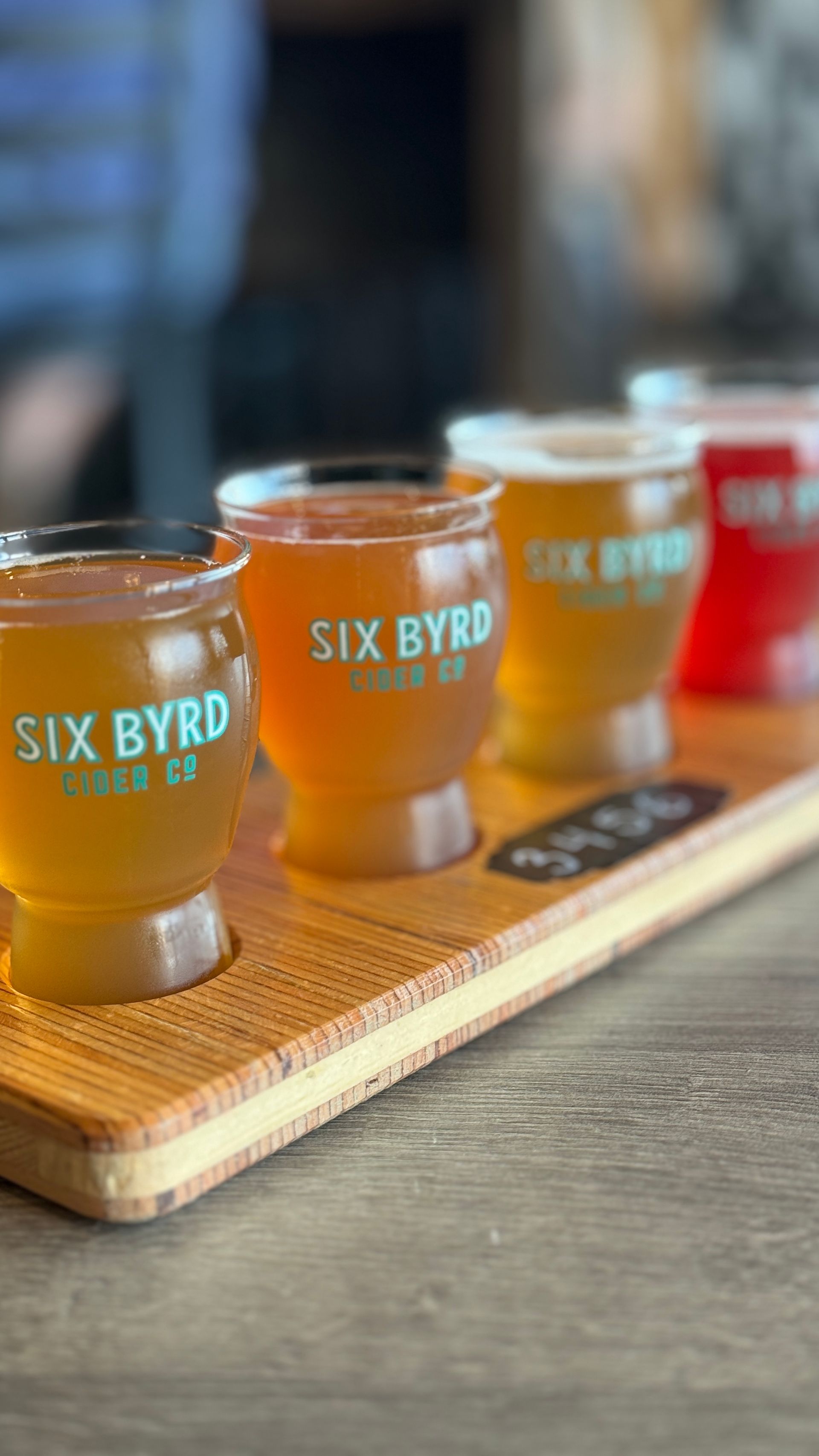 A wooden tray with four glasses of beer on it.