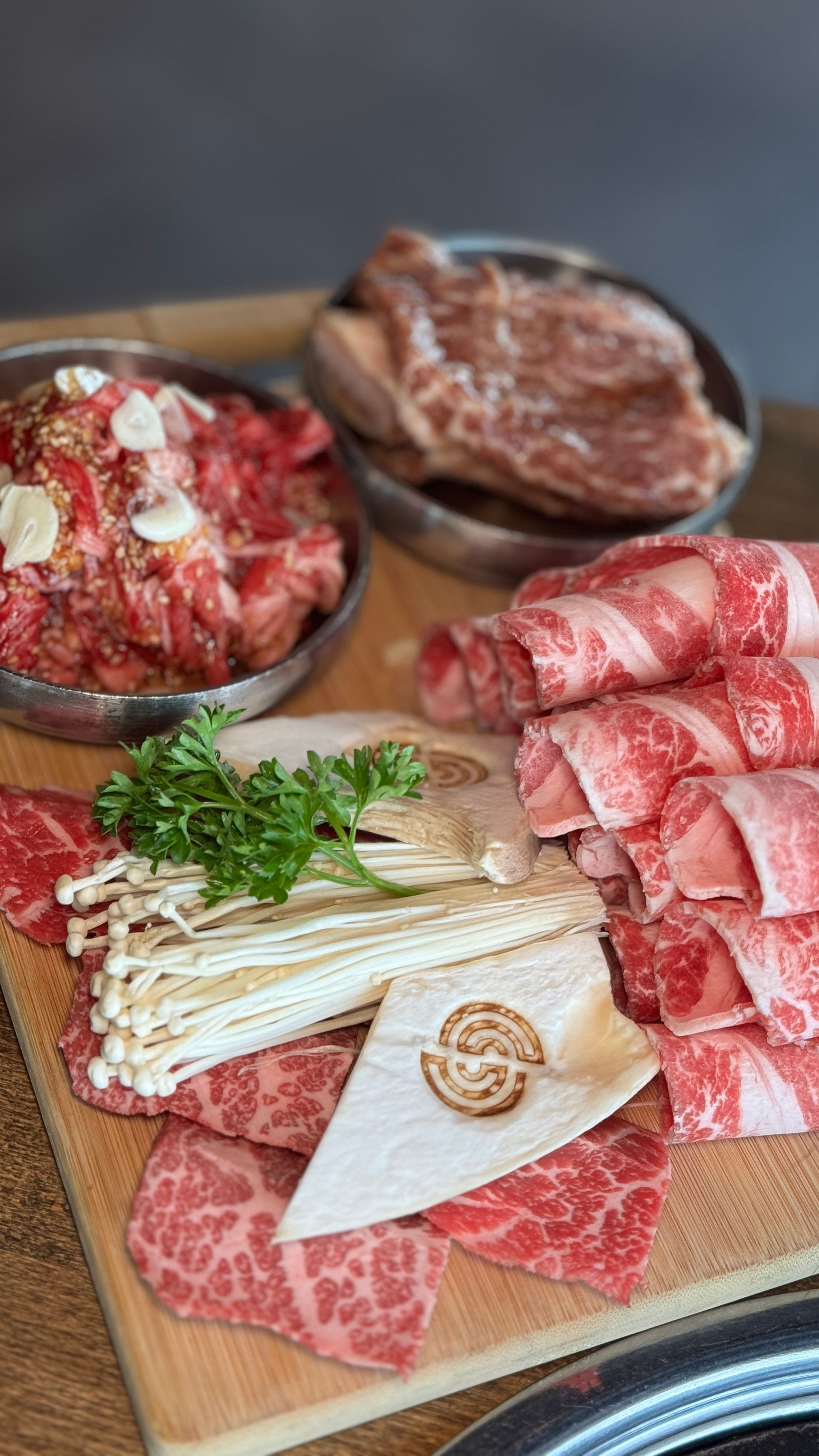 A wooden cutting board topped with a variety of meats and mushrooms.