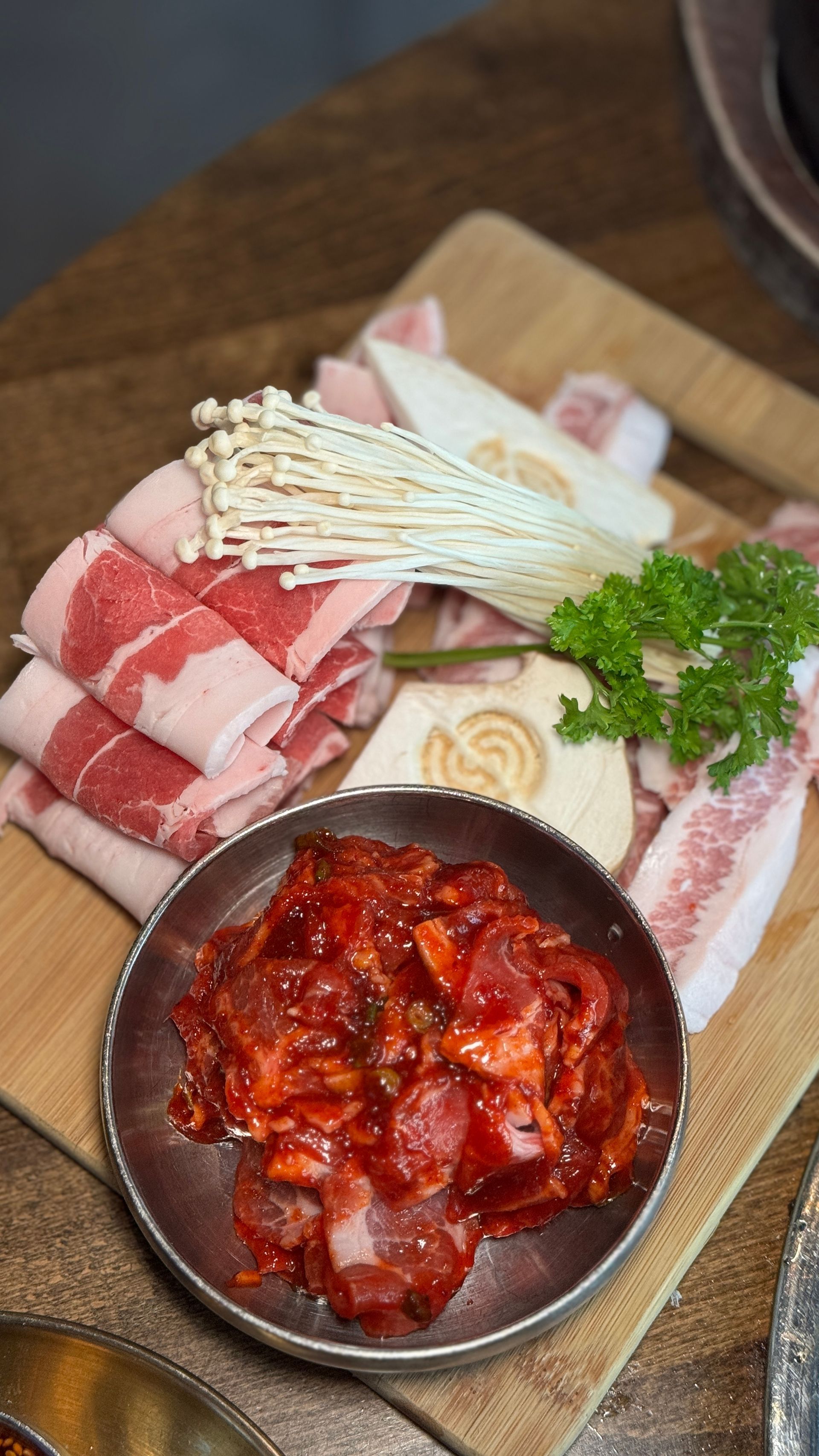 A wooden cutting board topped with meat , mushrooms and sauce.