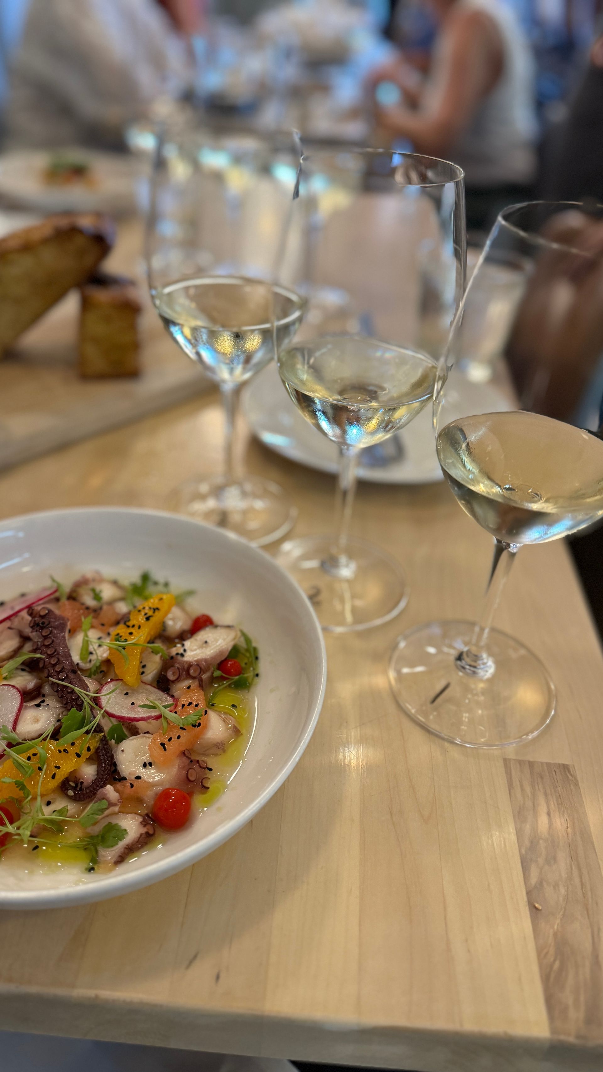 A plate of food and two glasses of wine are on a table.