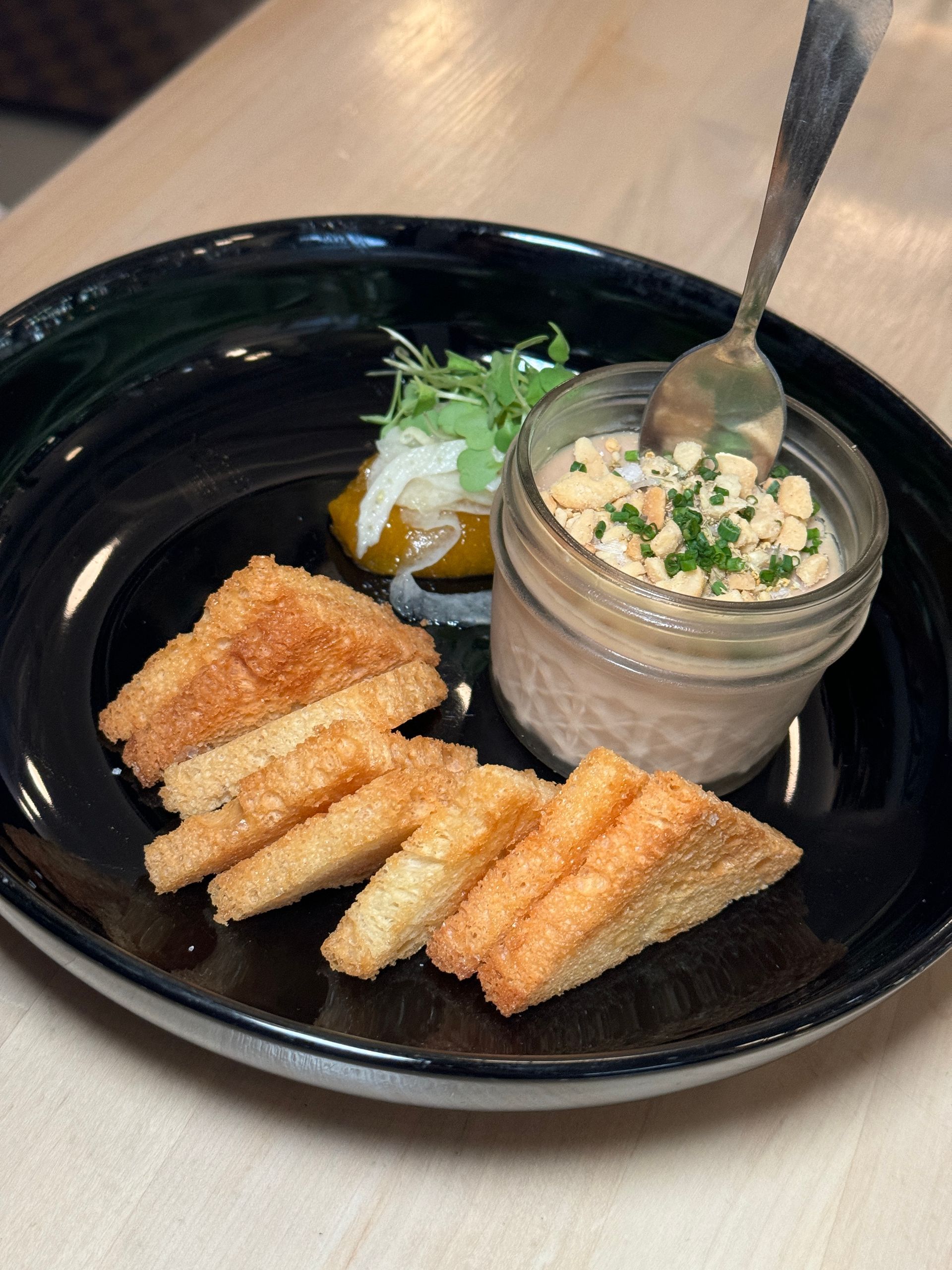 A plate of food with crackers and a jar of dip on a table.