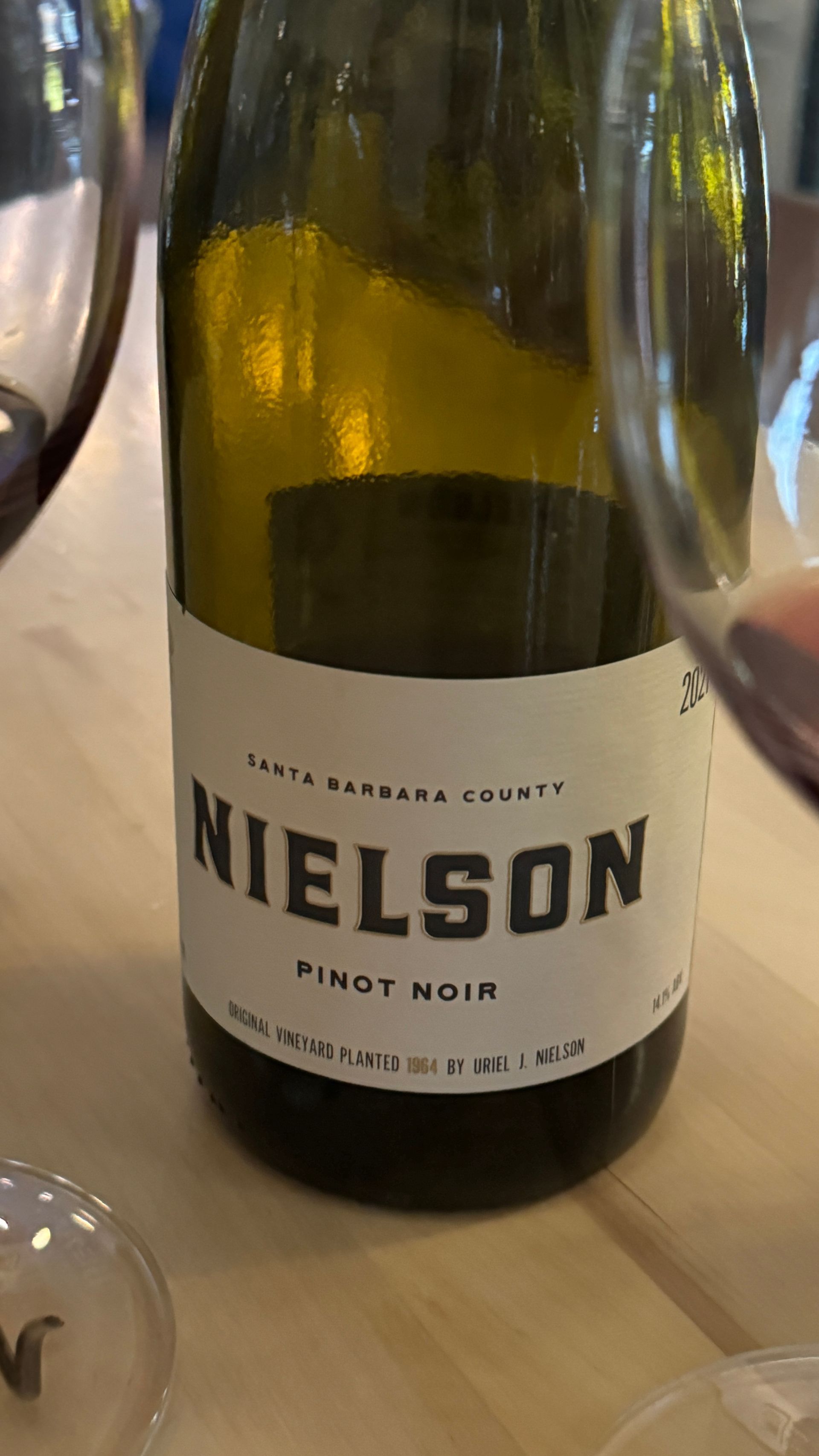 A bottle of nielson pinot noir wine is sitting on a table next to a glass of wine.