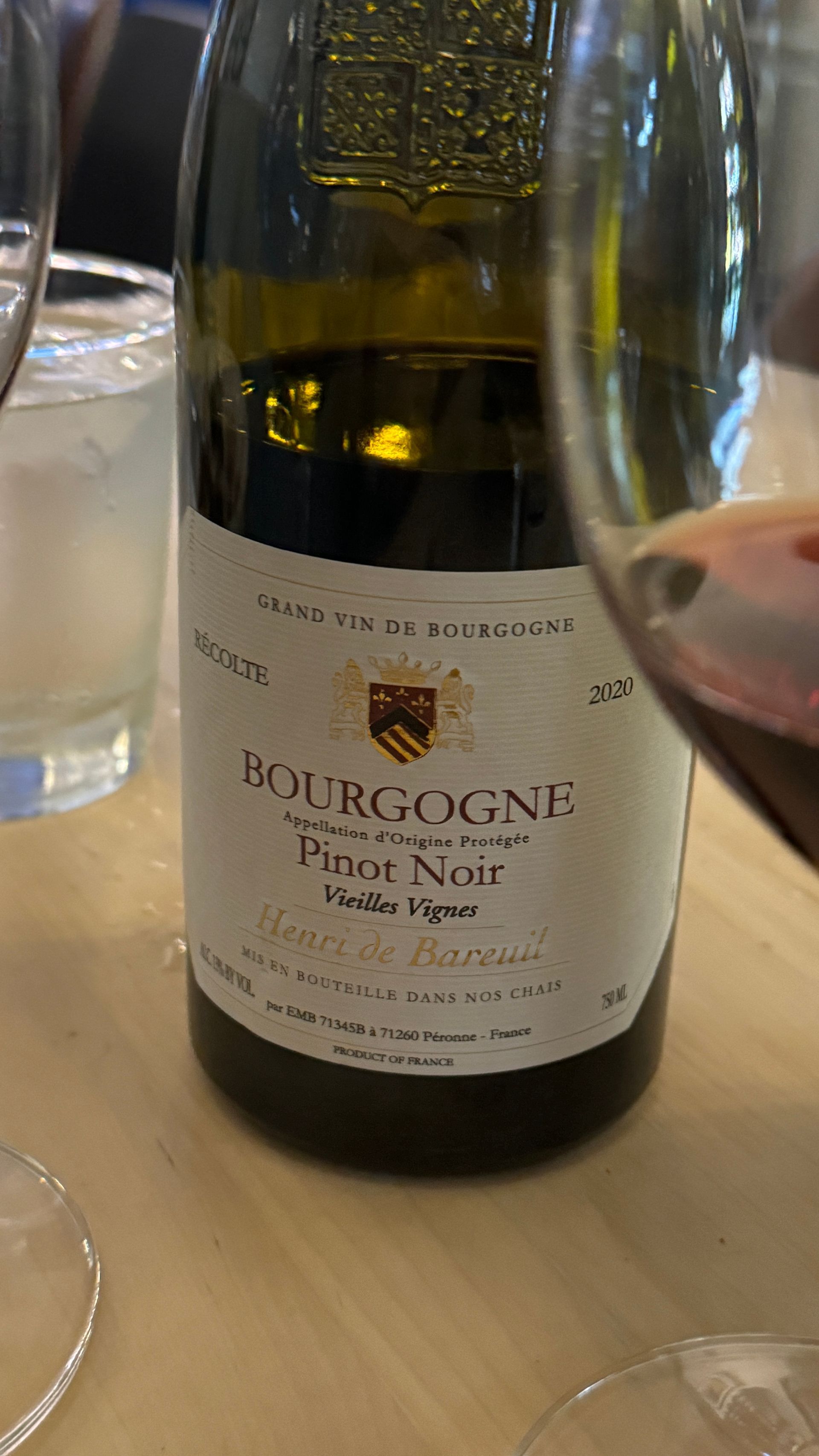 A bottle of pinot noir wine is sitting on a table next to a glass of wine.