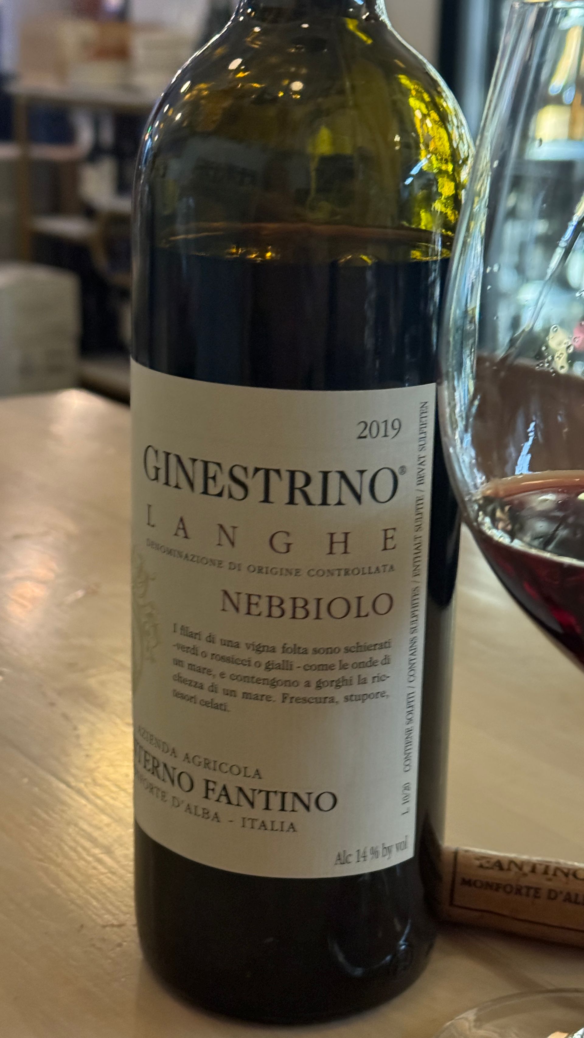 A bottle of ginestrone wine is on a table next to a glass of wine