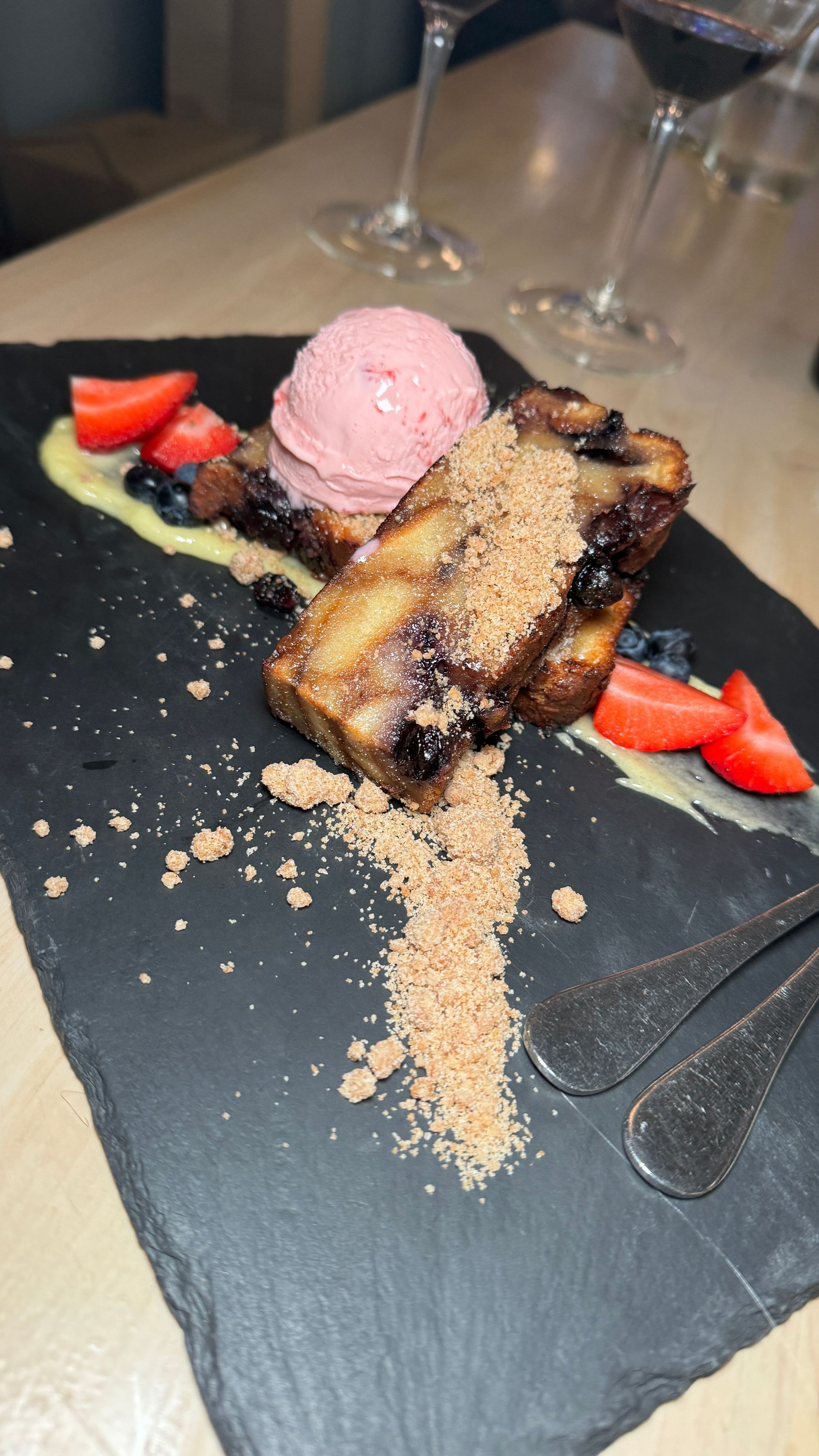 A plate of food with ice cream and strawberries on a table.