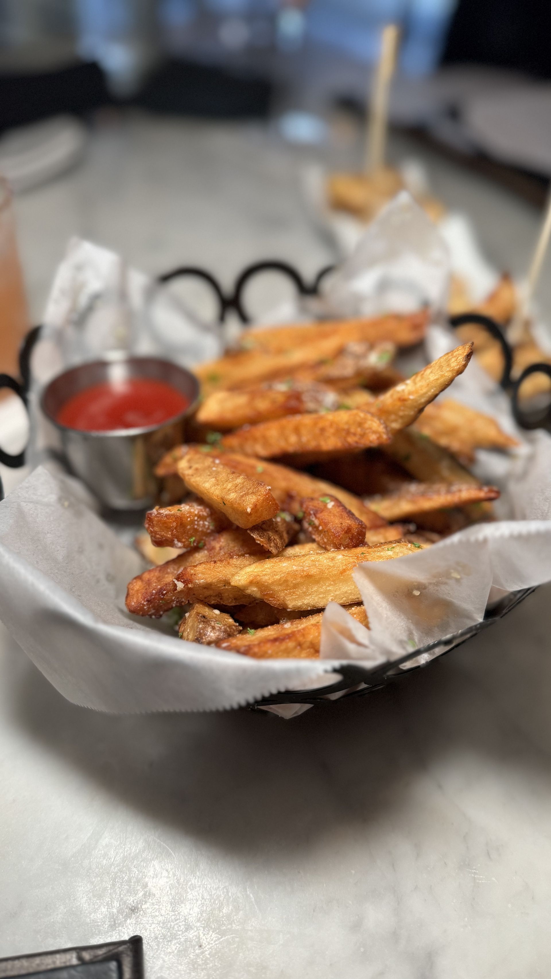 The Beverly - A basket of french fries with ketchup on a table.
