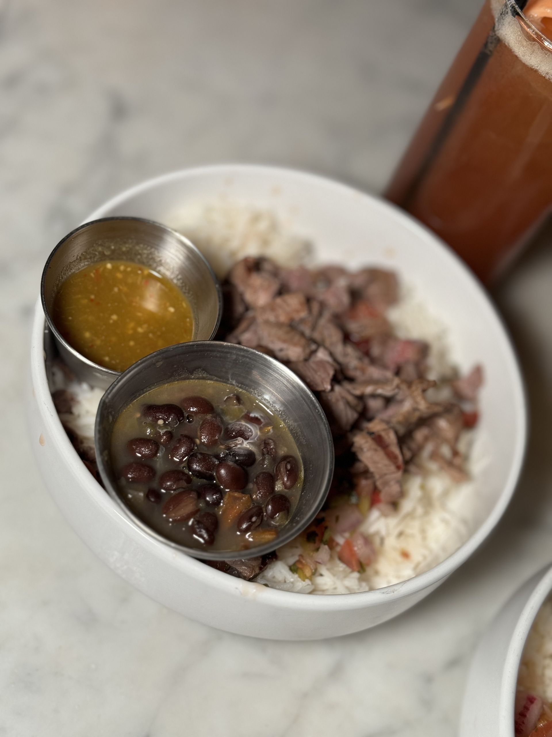 The Beverly - A bowl of food with beans and rice on a table.